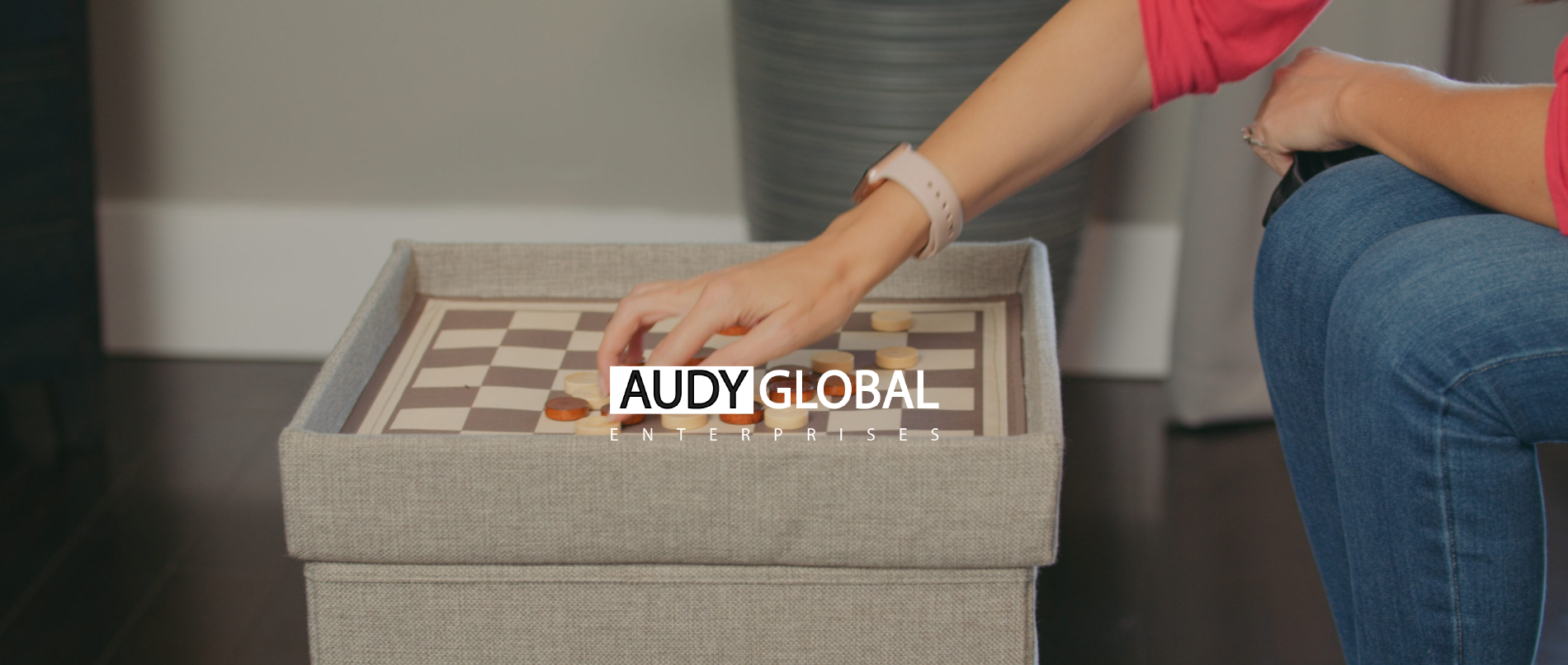 IU C&I Studios Page Audy Global Enterprises Logo on background side view of woman playing checkers