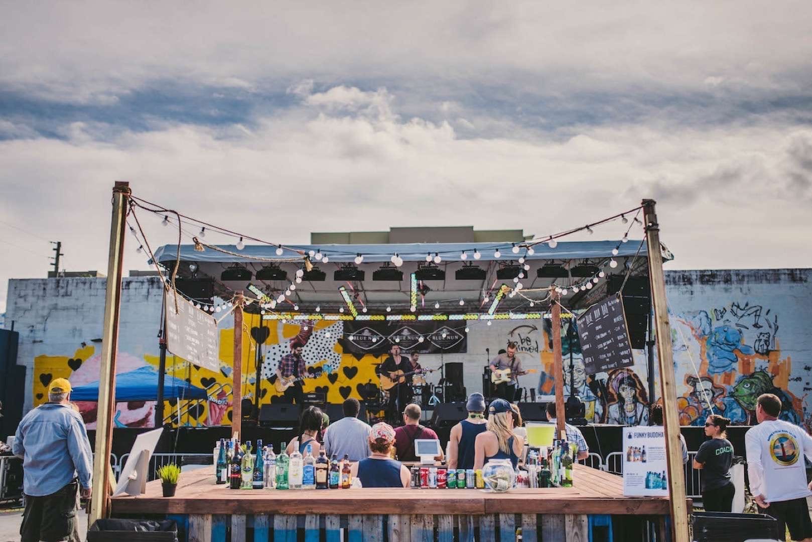 Performing for small crowd with bar with alcoholic and non-alcoholic drinks in the foreground For at the Love Music Festival 