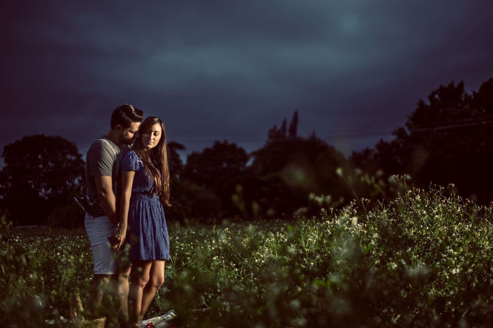 Man embracing a woman from behind in a field at night