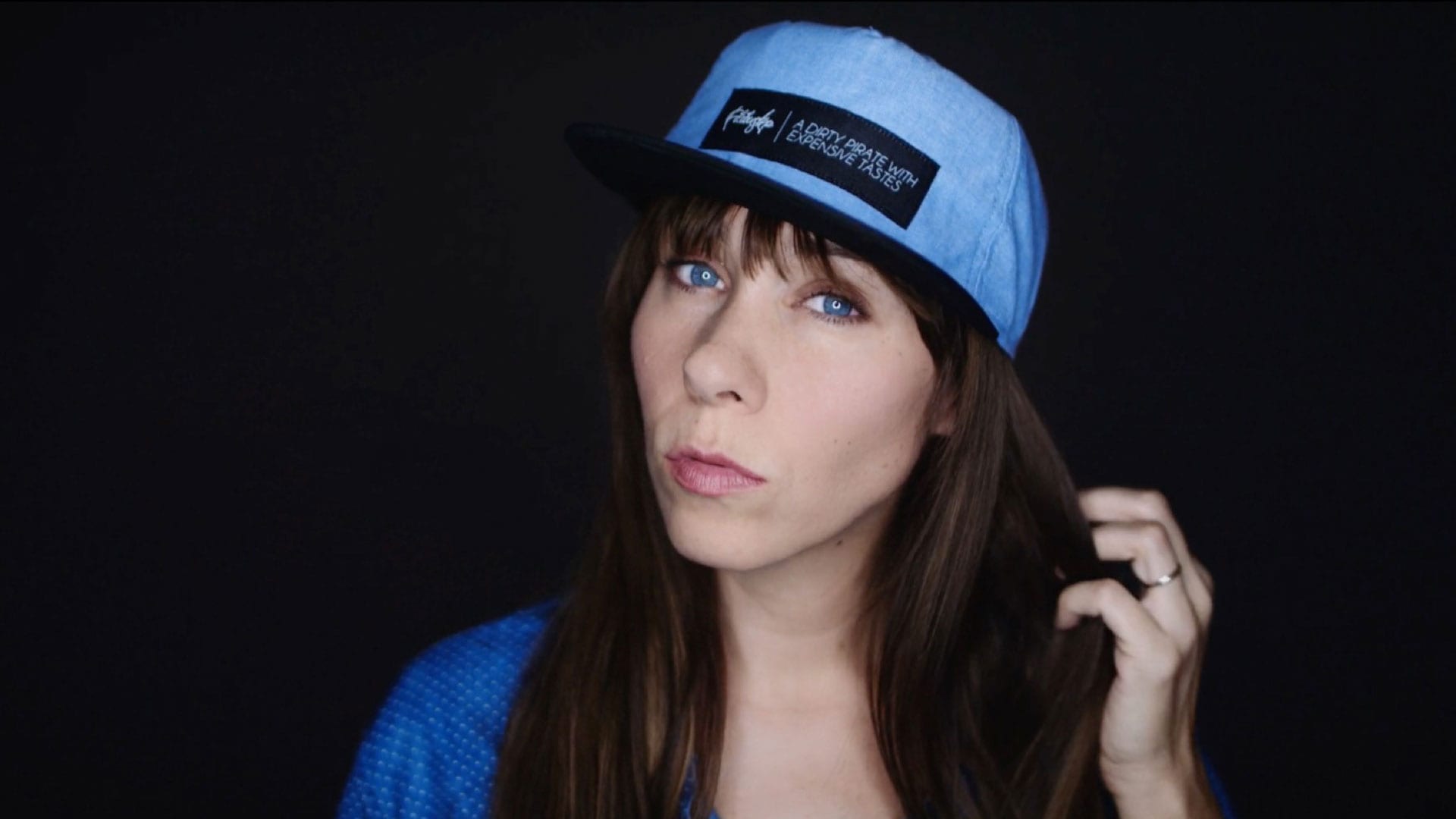 Filibuster Apparel Woman with long brown hair in a blue shirt wearing a light blue hat with black rim