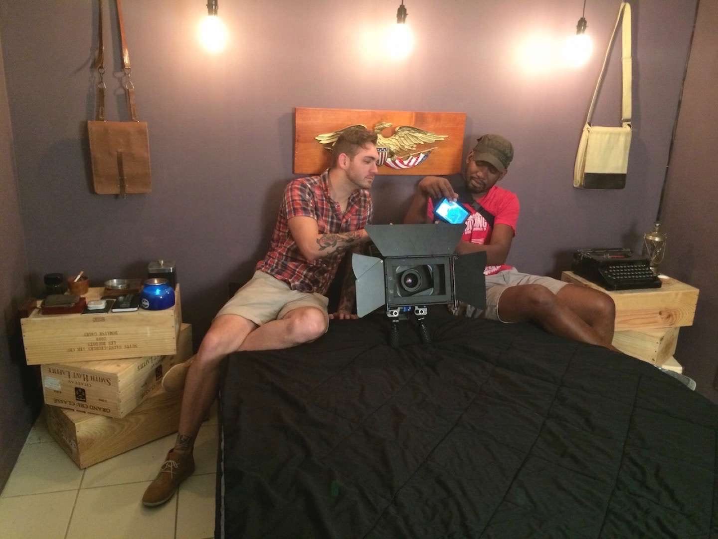 Two male film crew on a bed adjusting video equipment