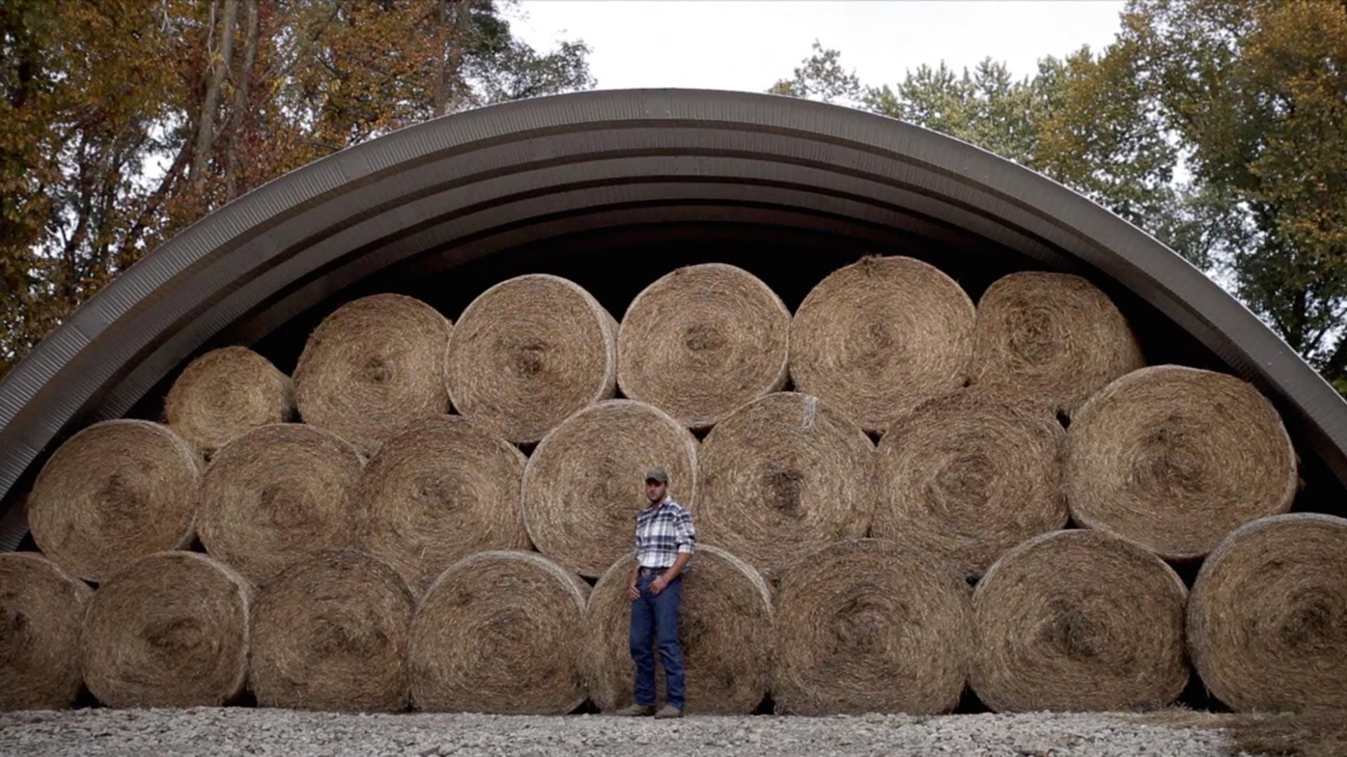 Peter Buttigieg standing in front of a hangar building filled with hay bales