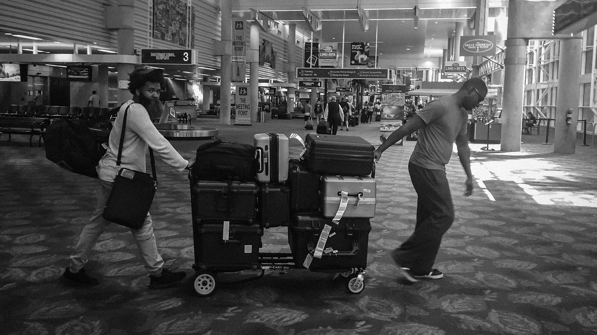 Black and white of two African American males moving film gear in Ft Launderdale airport