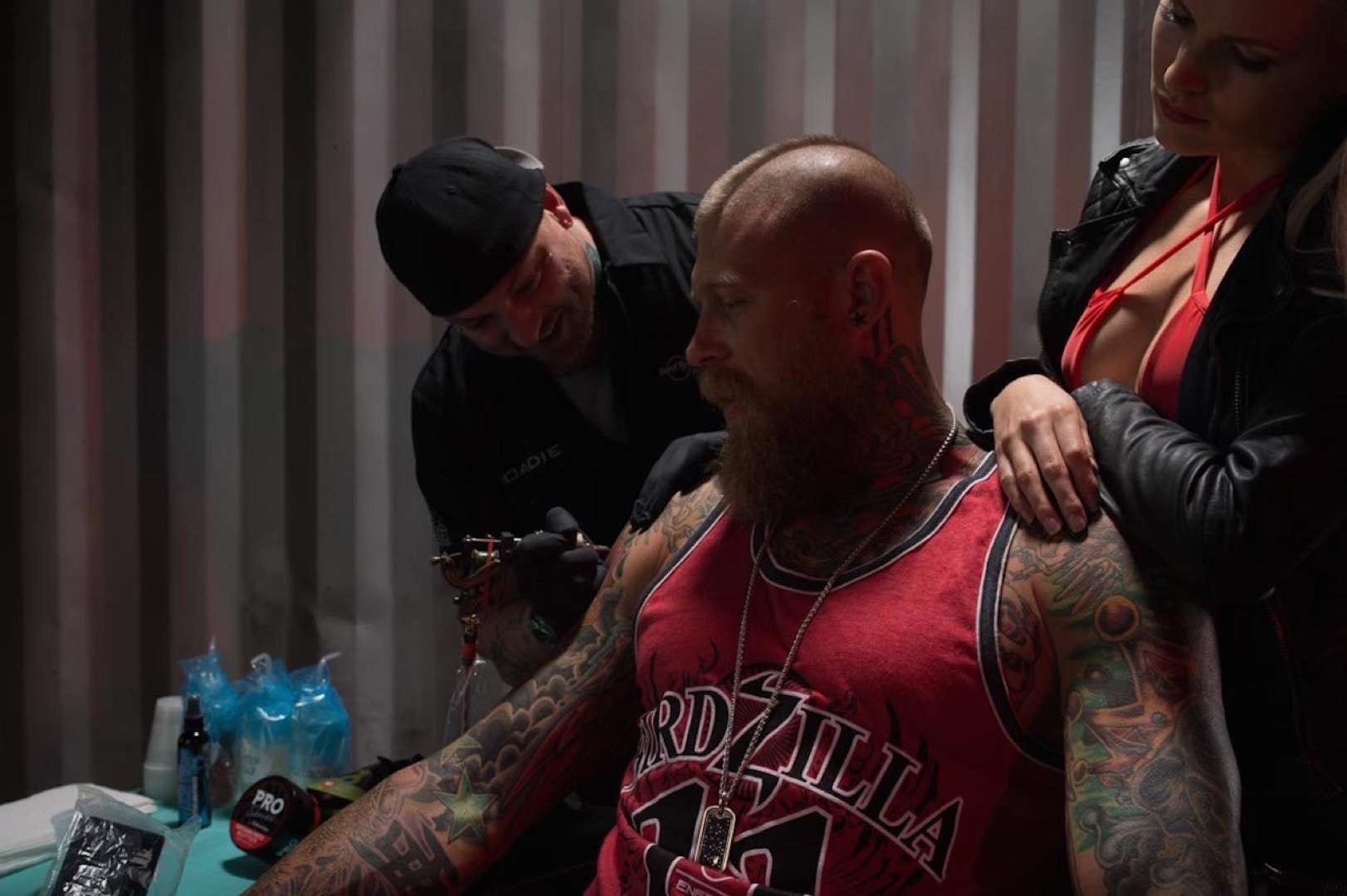 Tattooed man with mohawk getting tattooed by tattoo artist