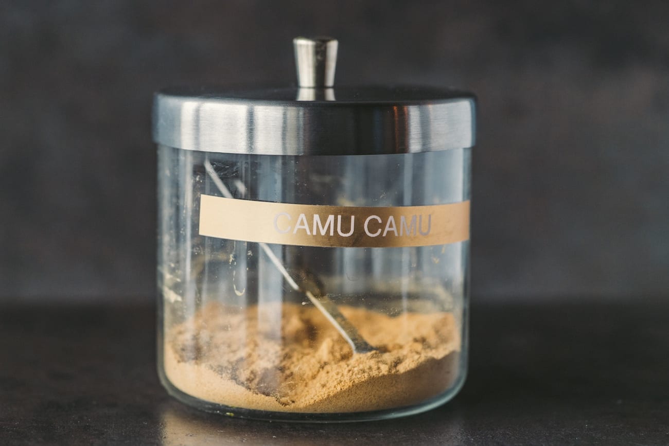 Camu Camu powder in a glass container with a scoop