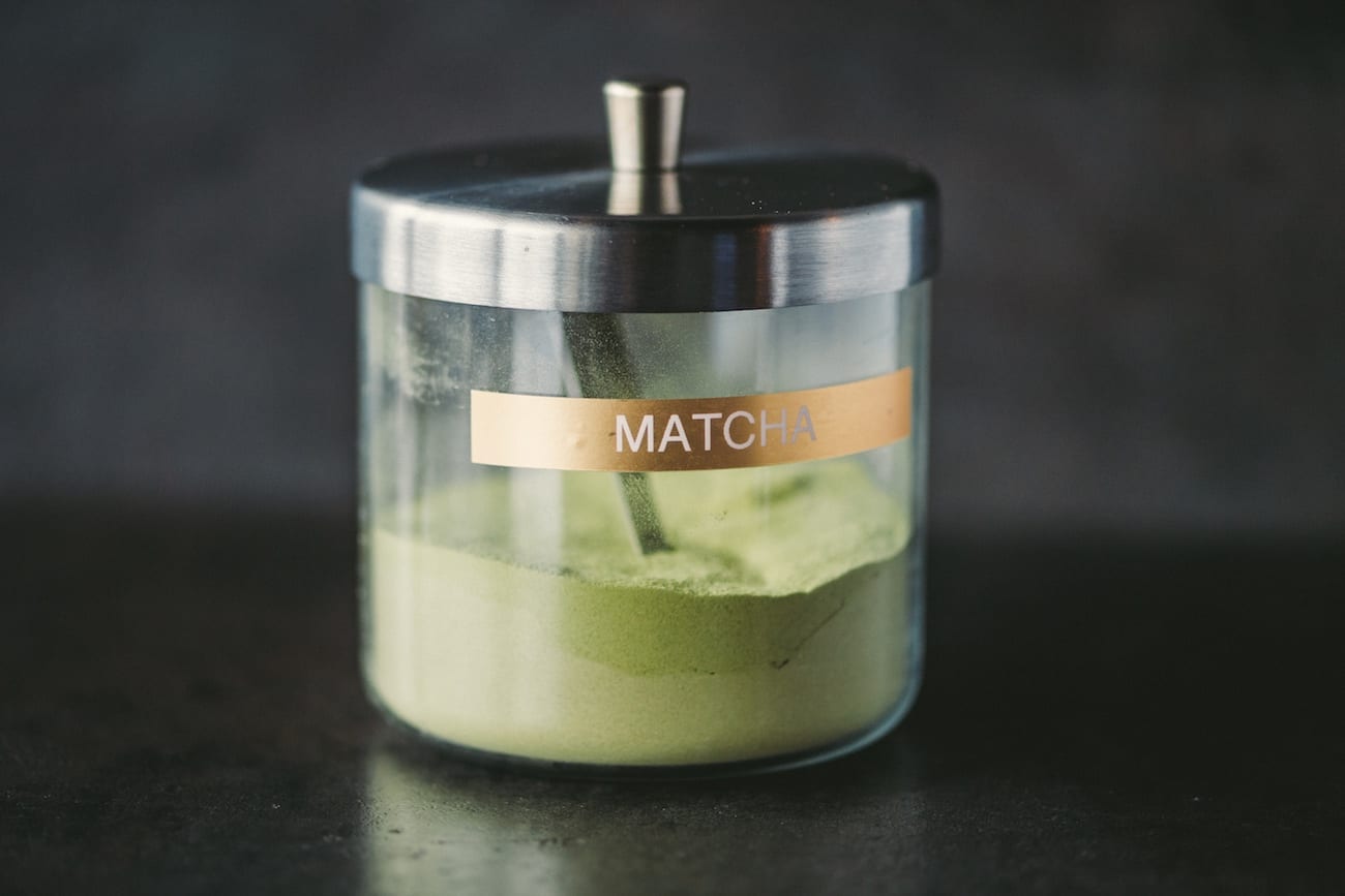 Matcha powder in a glass container with a scoop