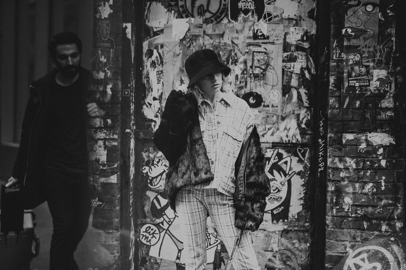 Black and white of woman standing in front of wall with graffiti posing for the camera