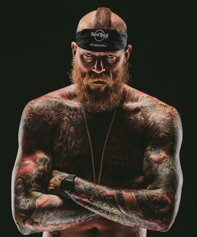 Hard Rock Energy 20 Bearded tattooed man posing for camera with arms crossed