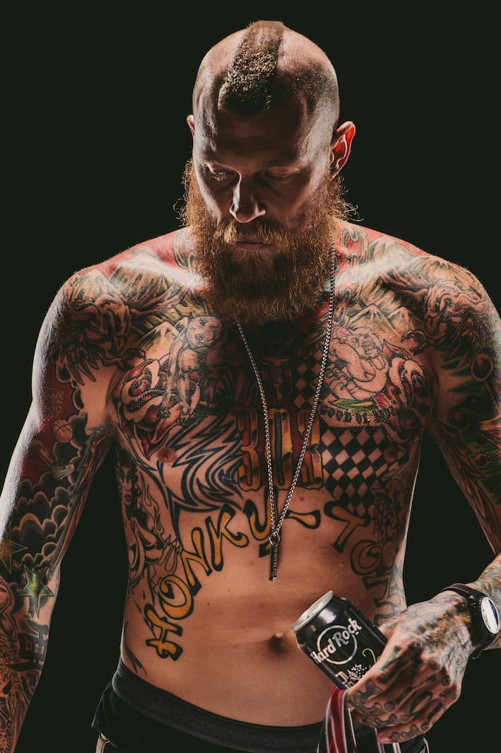 Bearded tattooed man posing for camera holding a can of Hard Rock Energy drink