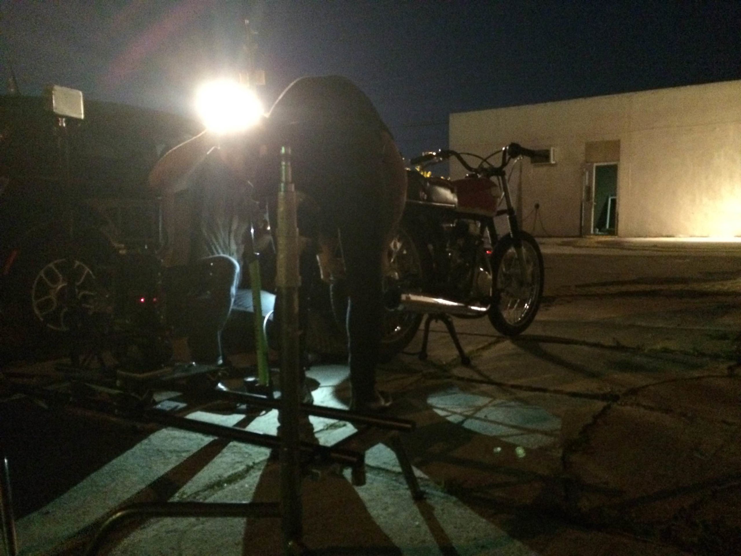 Crew members working near motorcycle in the dark with a light