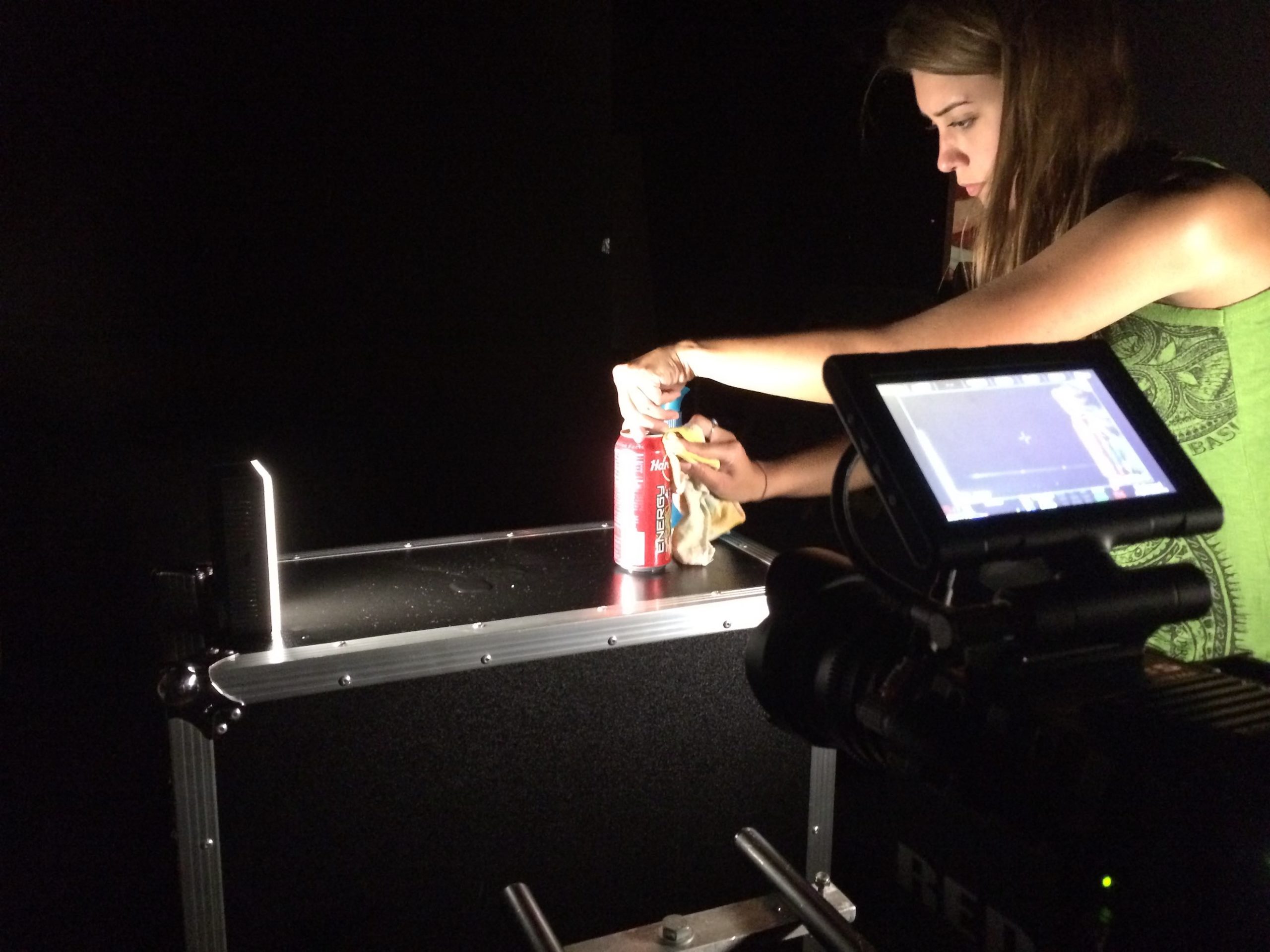 Woman opening a can of Hard Rock Energy drink surrounded by equipment