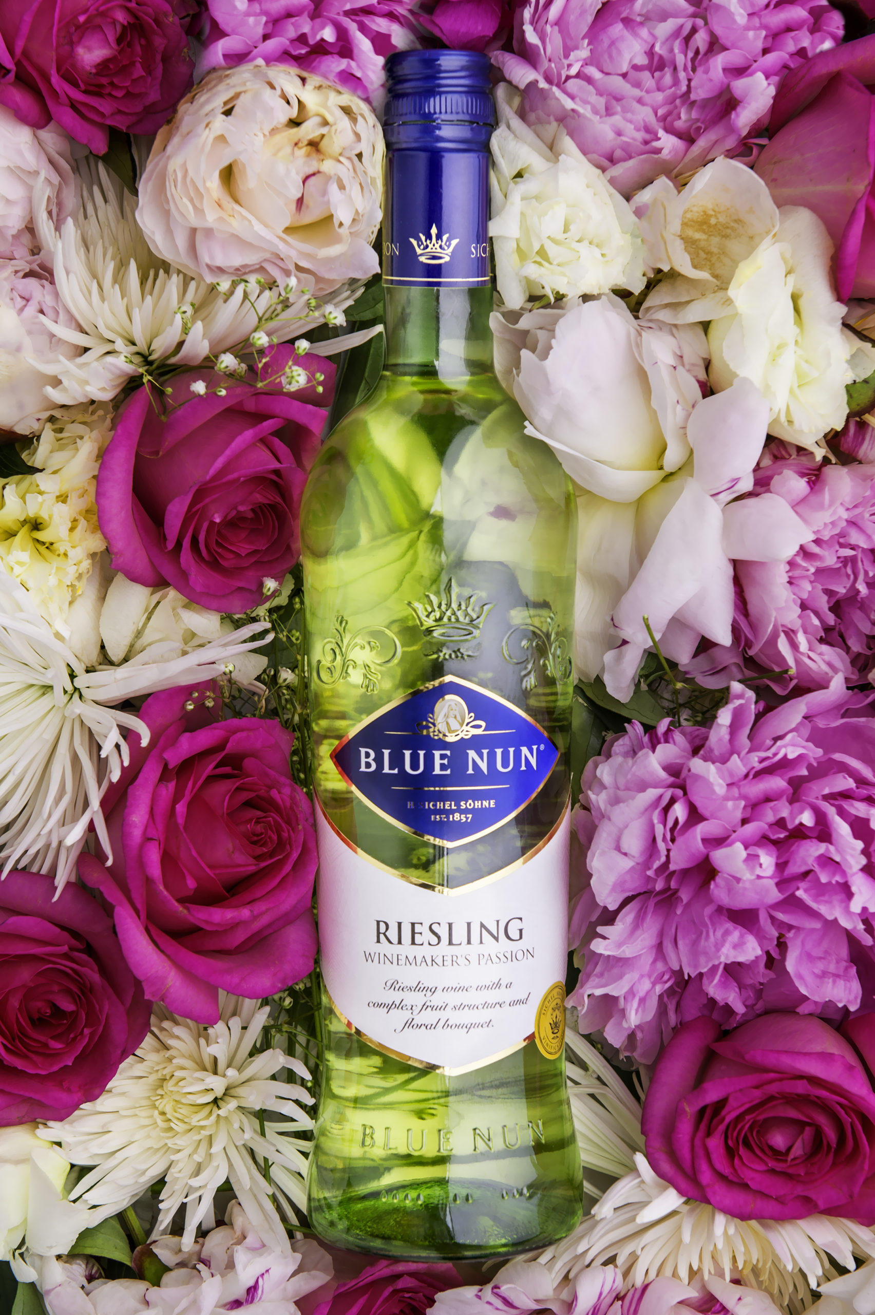 Bottle of Riesling wine on display with various flowers in the background