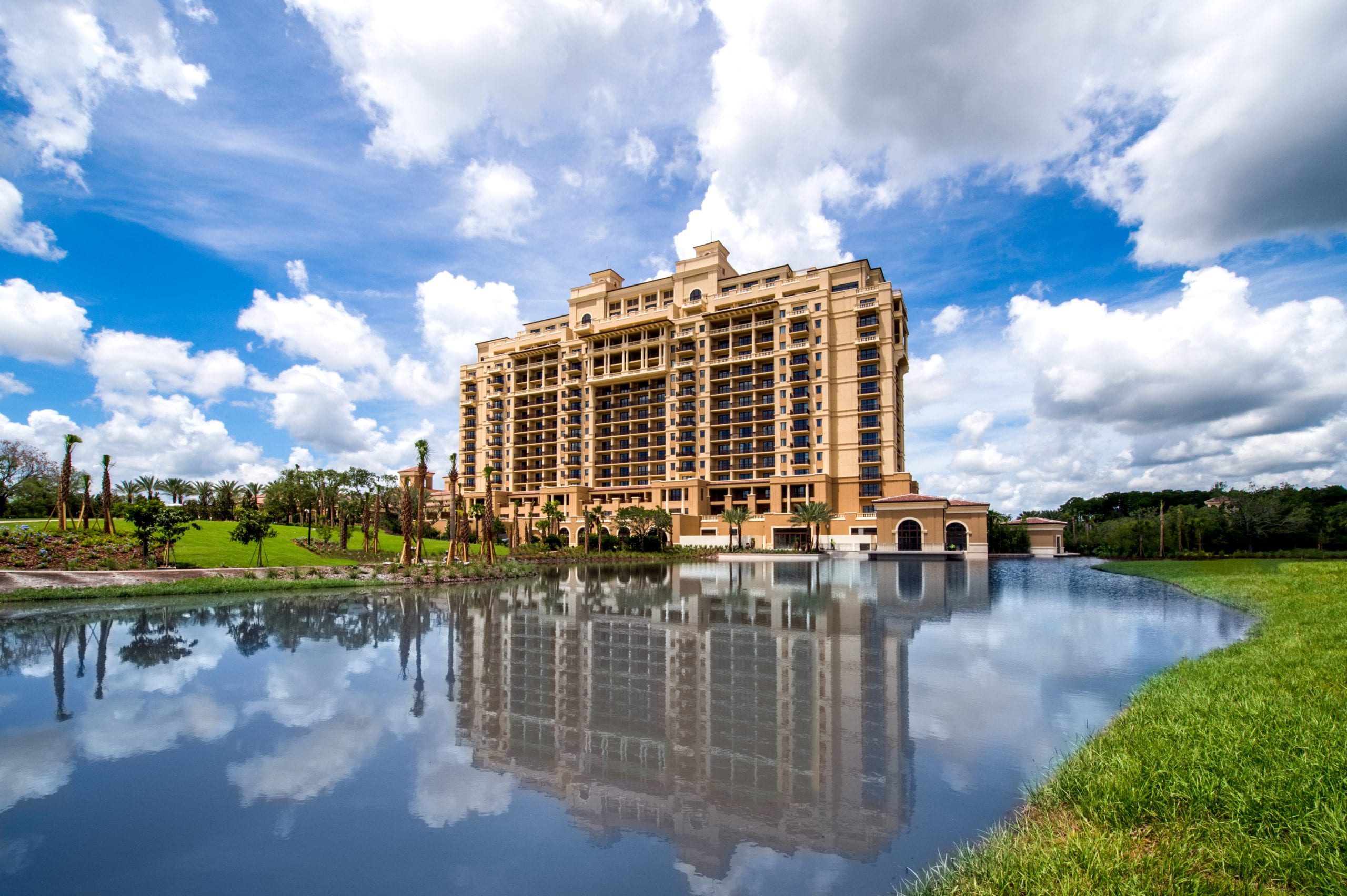 Four Seasons Building by pond under blue cloudy skies with palm trees
