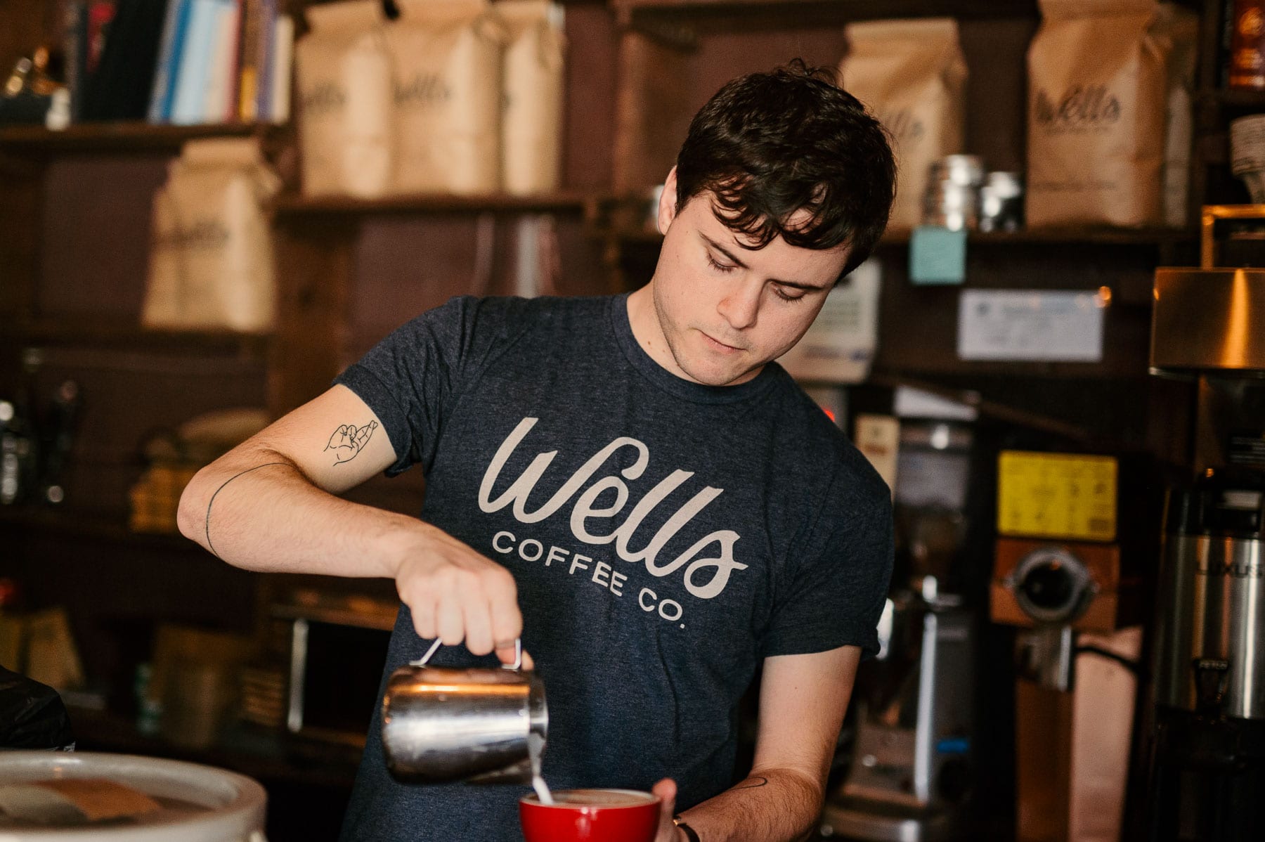 Staff member pouring milk in a cappuccino