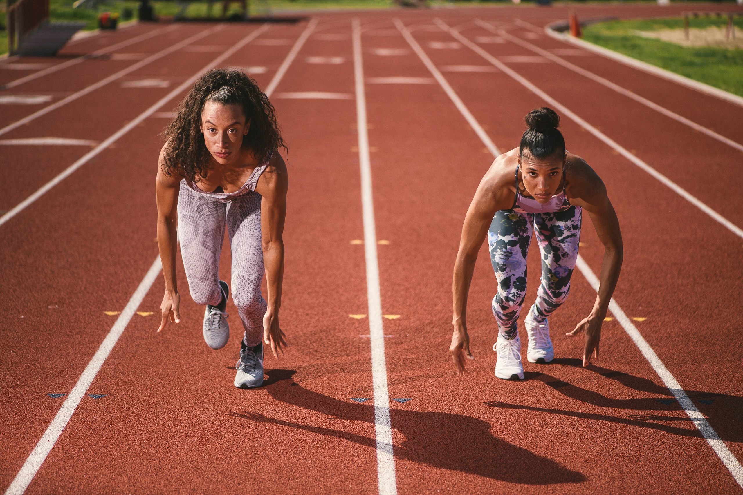 Professional Photography Services to elevate your brand C&I Studios Creative Marketing Kinetix 365 Two women posing for camera on a track field in track outfits poised to run