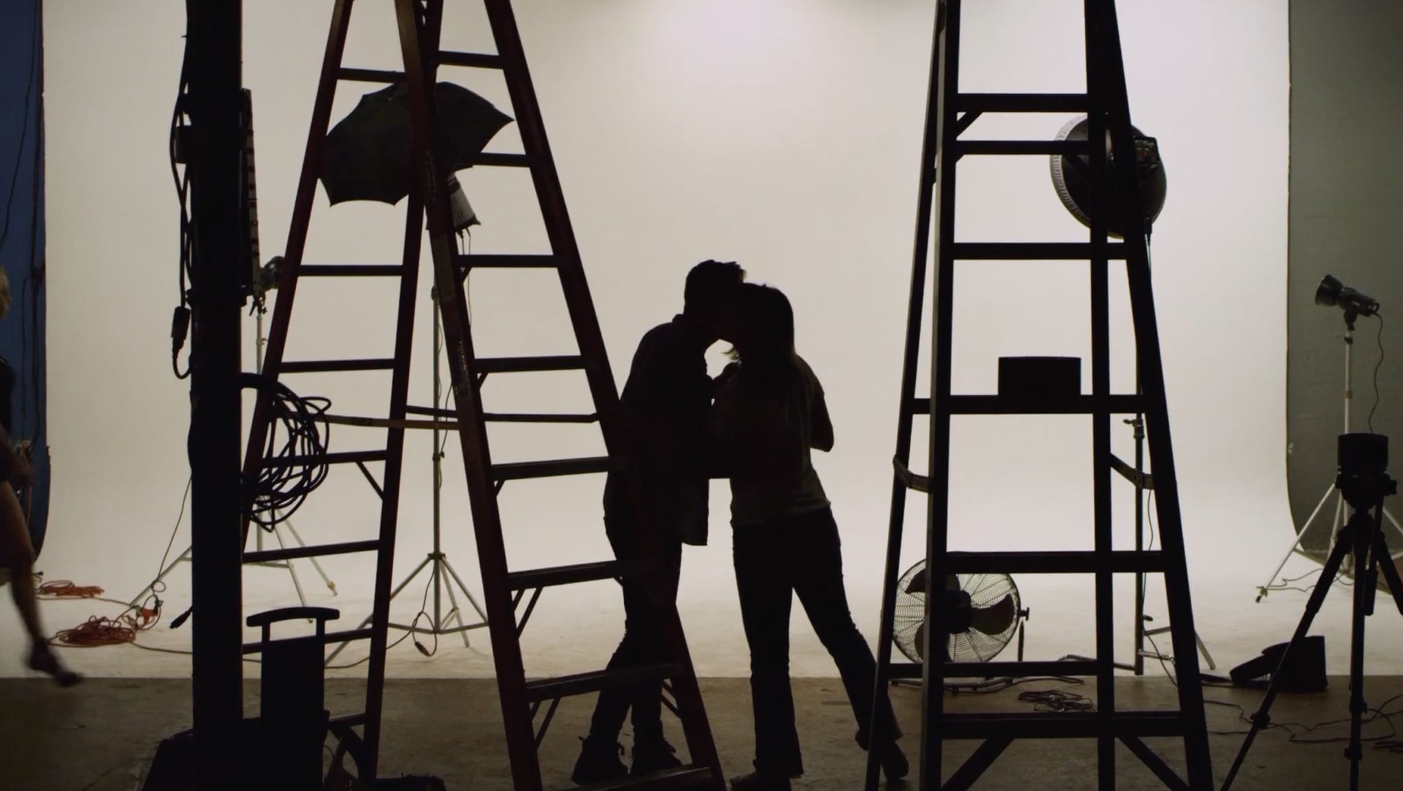 Two lovers backstage kissing among stage equipment