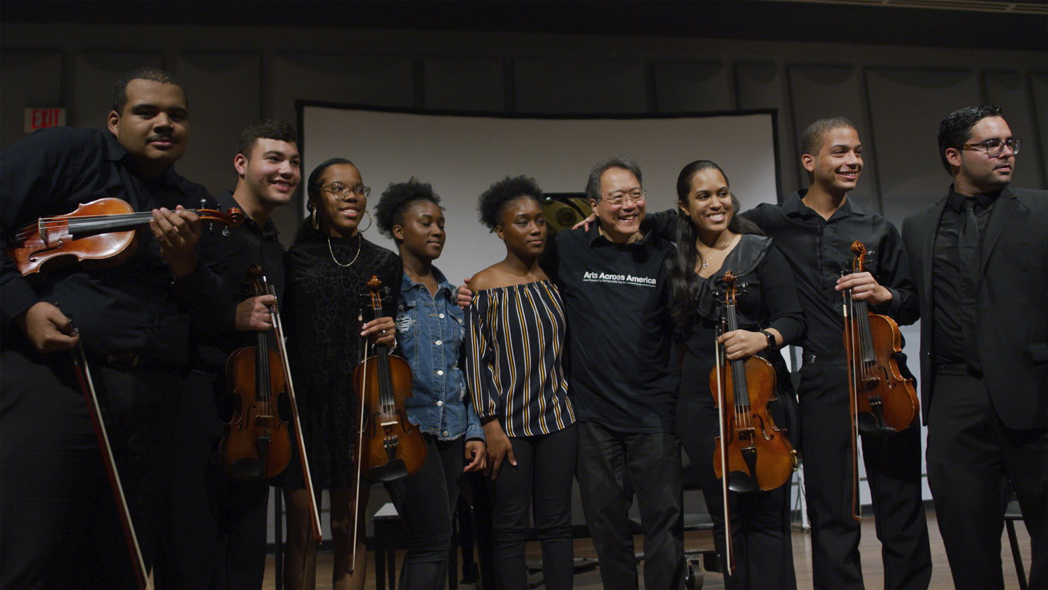 The Kennedy Center Yo-Yo Ma posing with a student band with many holding violins