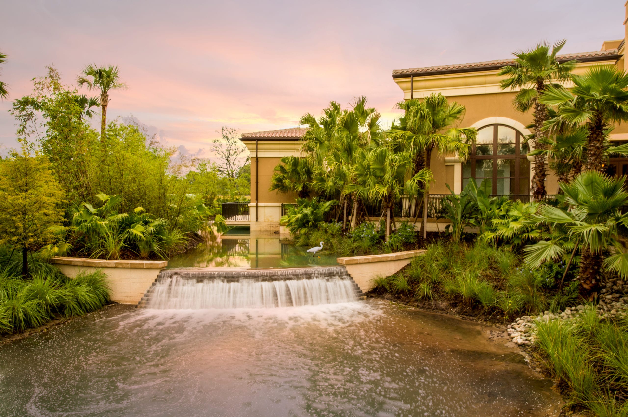 Four Seasons Building with waterfall, foliage, trees and palm trees at dusk