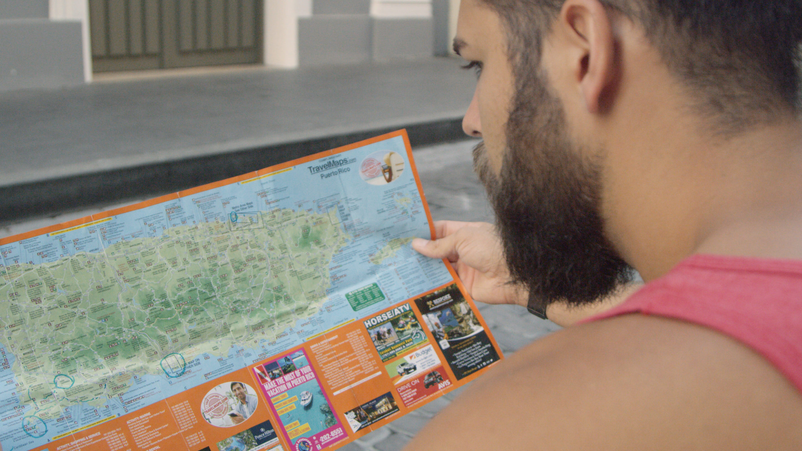 Blackmile Closeup look over the shoulder of a man with a bushy beard looking at a map of Puerto Rico island