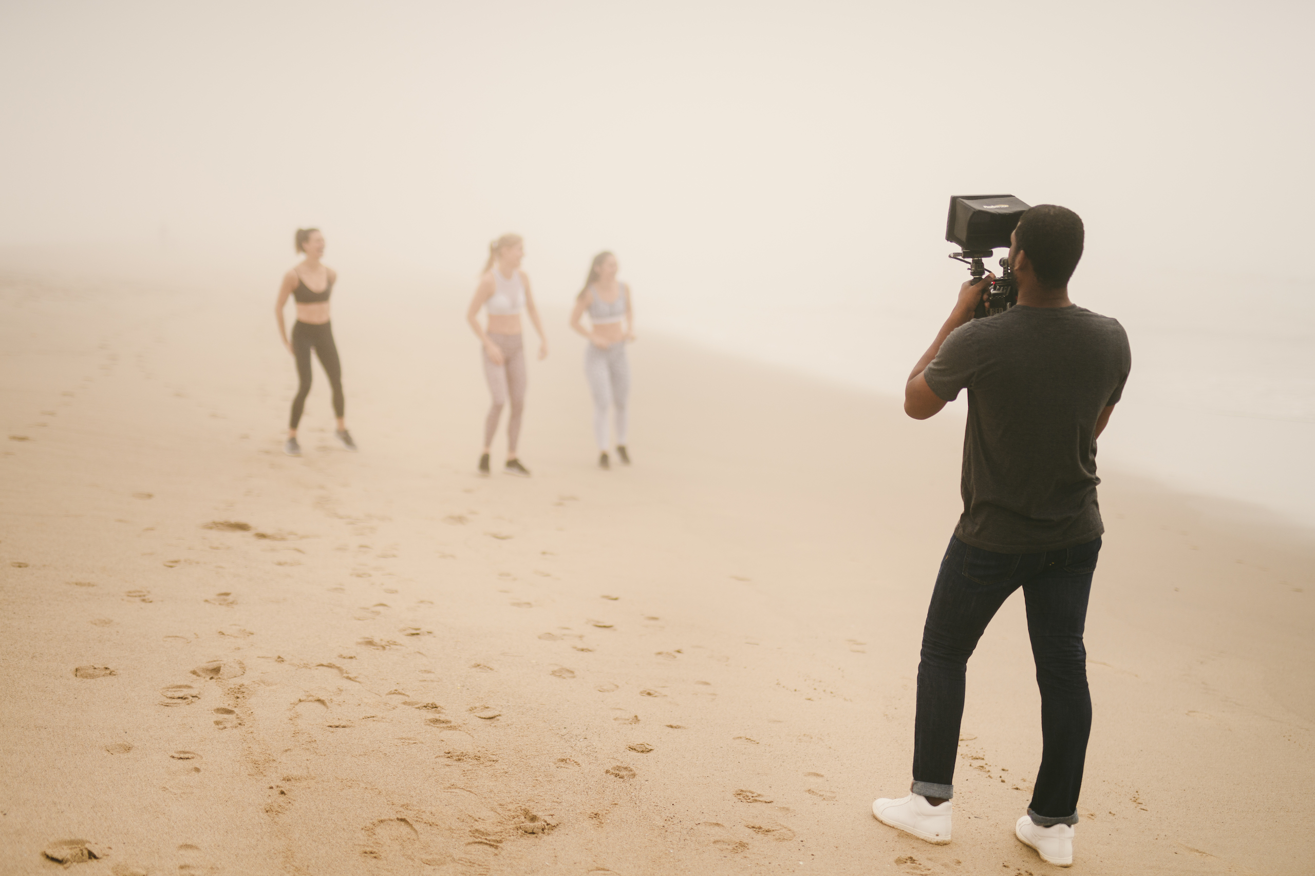 Health and Fitness Marketing Kinetix 365 Beach Exercises BTS Three women standing on the beach with a videographer filming them