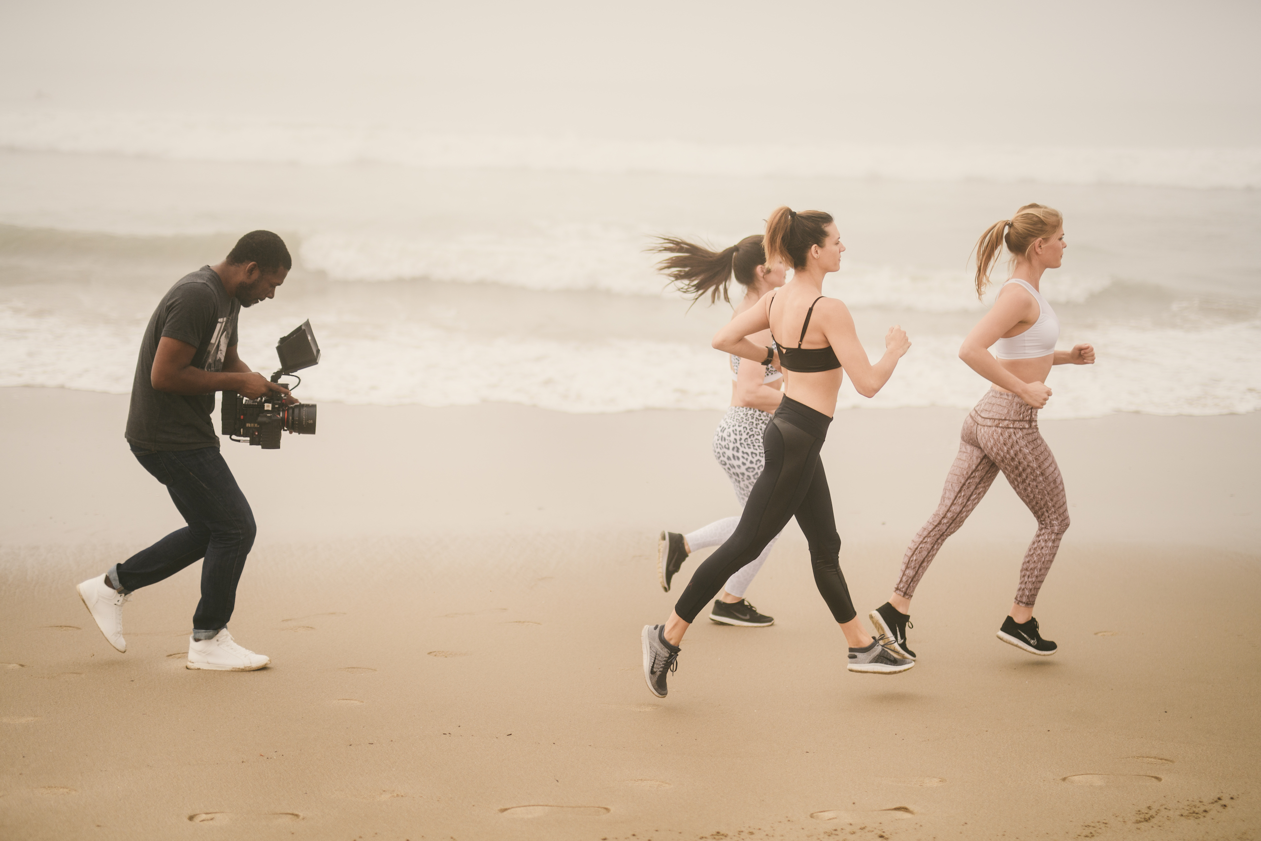 Health and Fitness Marketing Kinetix 365 Beach Exercises BTS Three women running on the beach with a videographer filming them from behind
