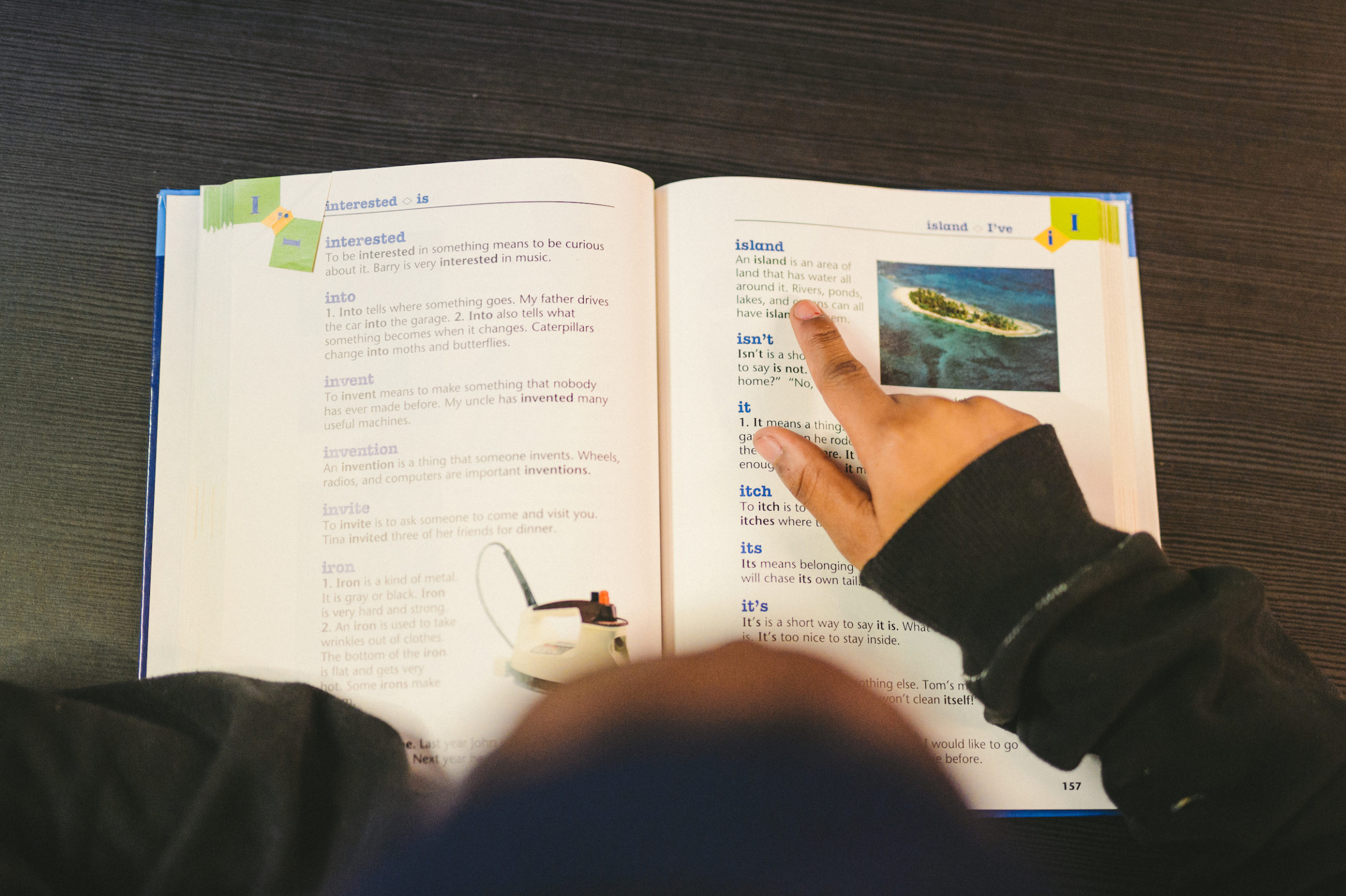 Overhead view of a student pointing to an island definition entry in a book