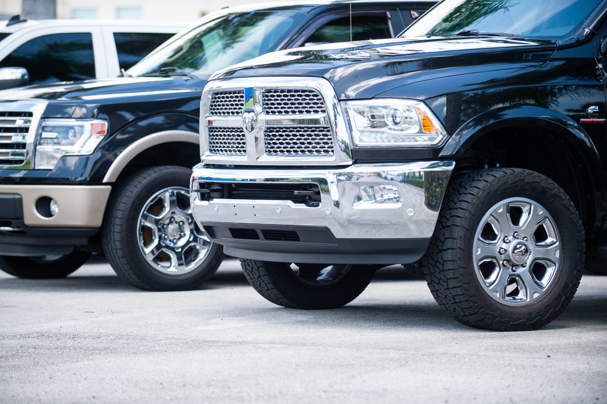 Front-side views of two black Dodge Ram trucks with heavy duty wheels with silver alloy.