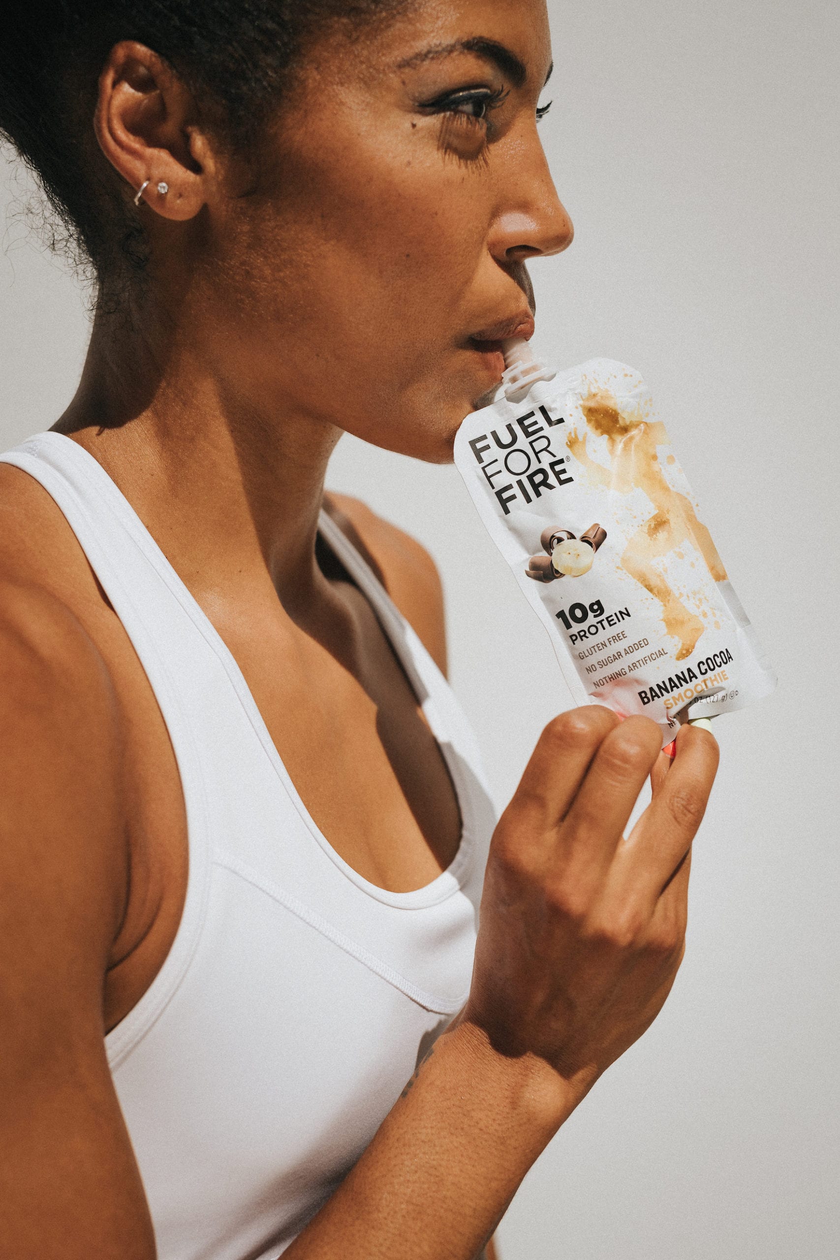 Karelle Edwards side profile closeup headshot of her drinking from a packet of Fuel for Fire Banana Cocoa smoothie