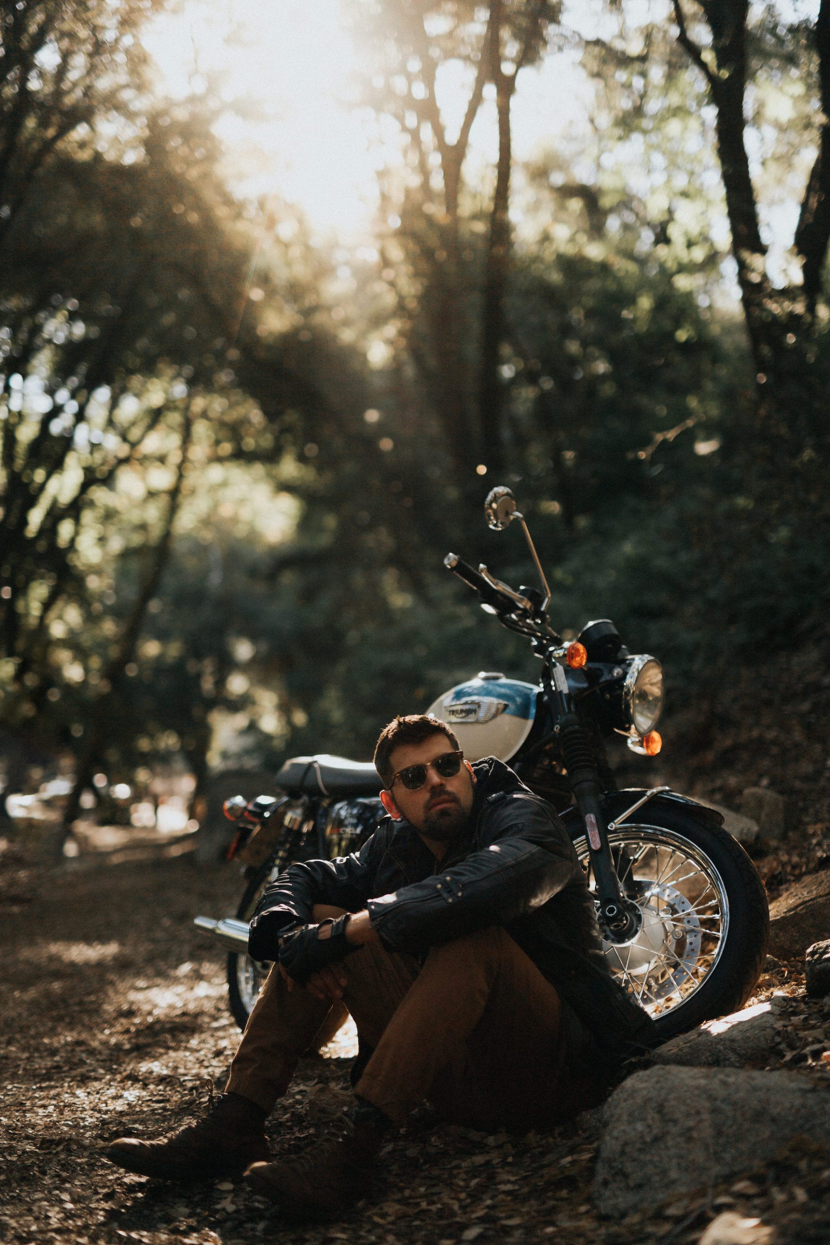 Smiling young biker leaning on motorcycle on road against sky stock photo -  OFFSET