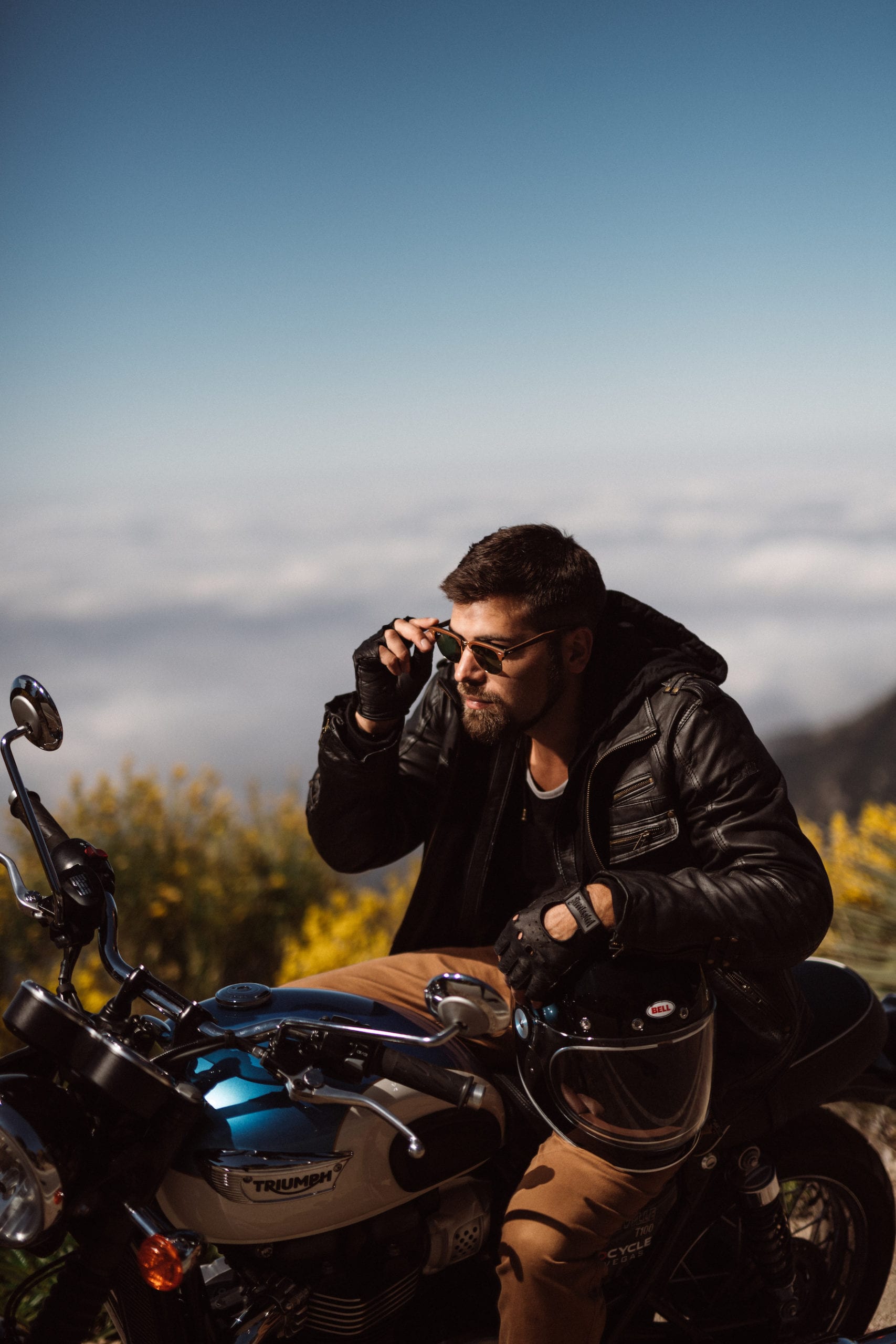 Motorcycle rider adjusts Ray-Ban Clubmaster sunglasses on his motorcycle before resuming the road trip.