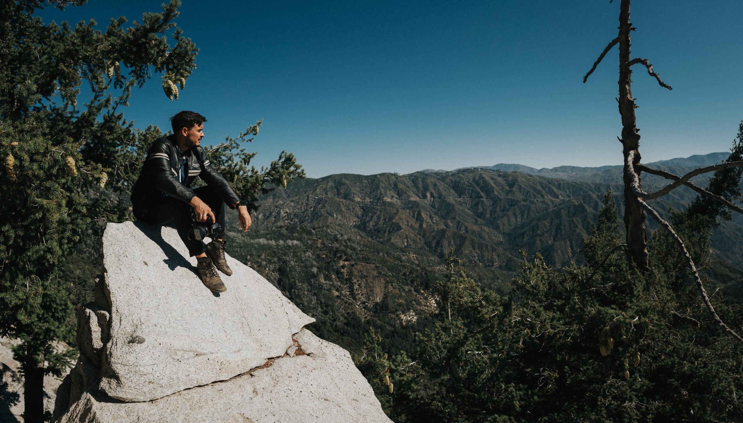 Angeles National Forest Photography Photographer overlooking forest canopy while perched atop a slanted rock face.