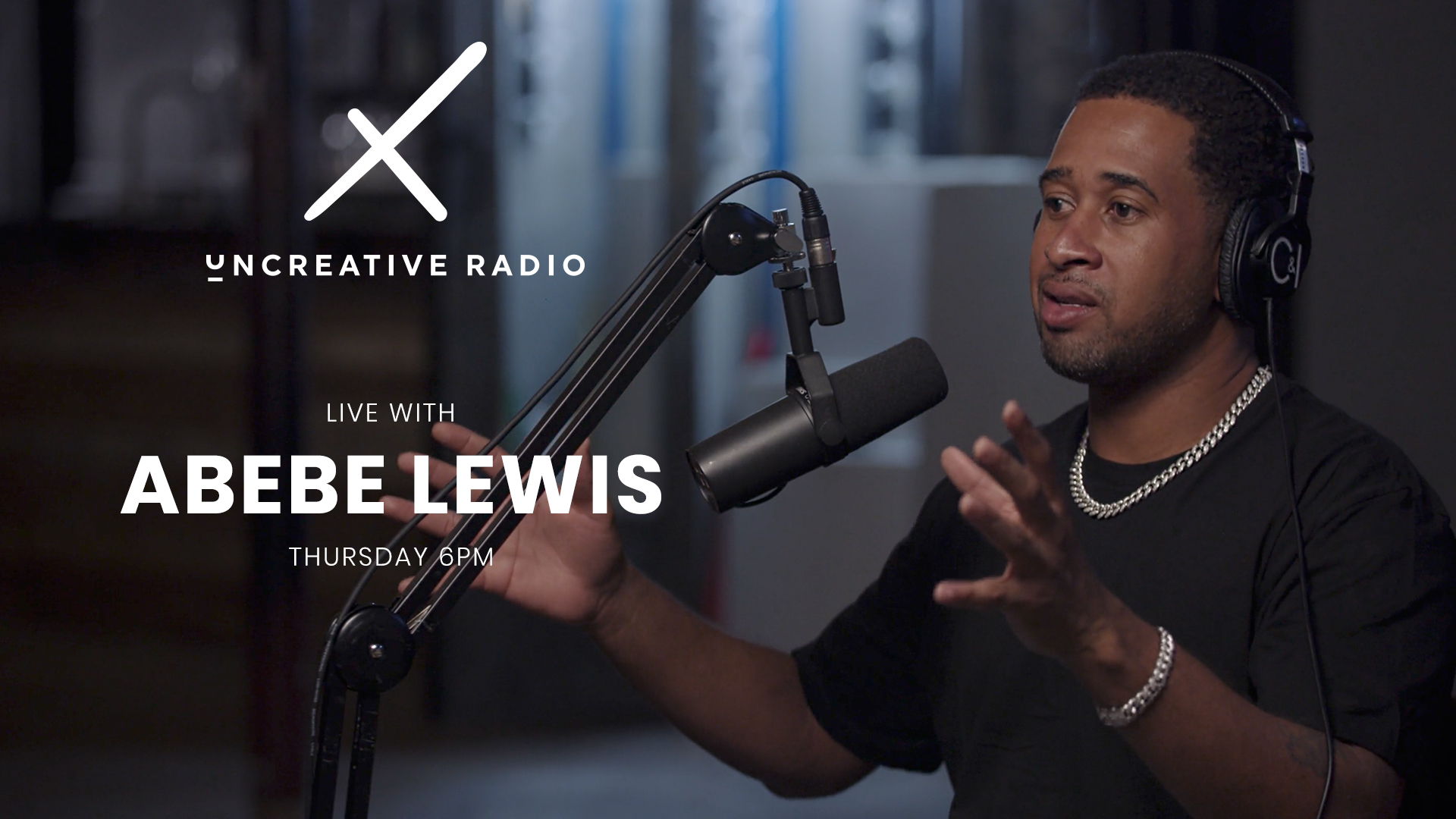 IU C&I Studios Page Uncreative Radio Live with Abebe Lewis title wearing black headphones by microphone gesturing with arms and hands in the air