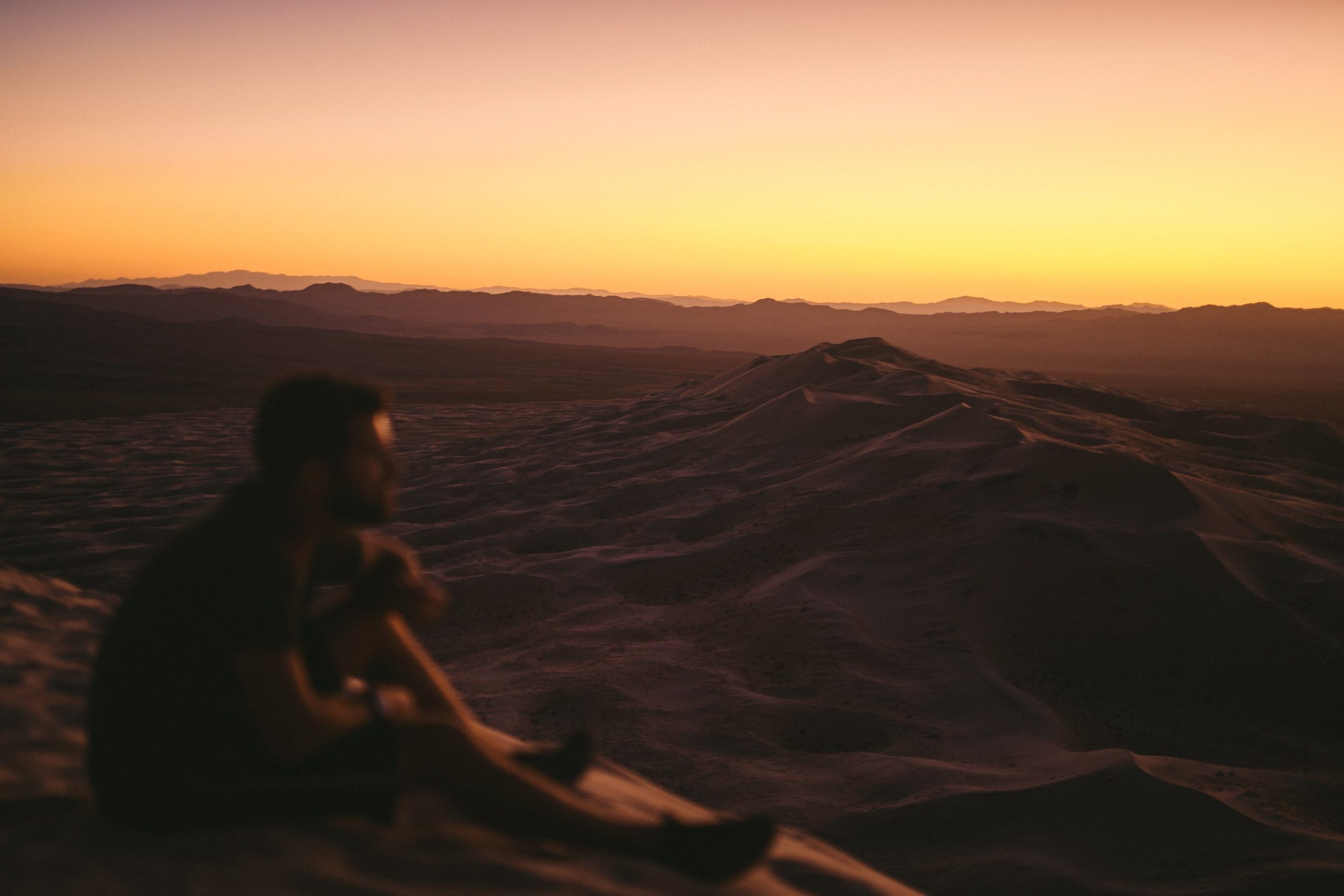 Blurry image of a bearded man sitting on a sandy cliff