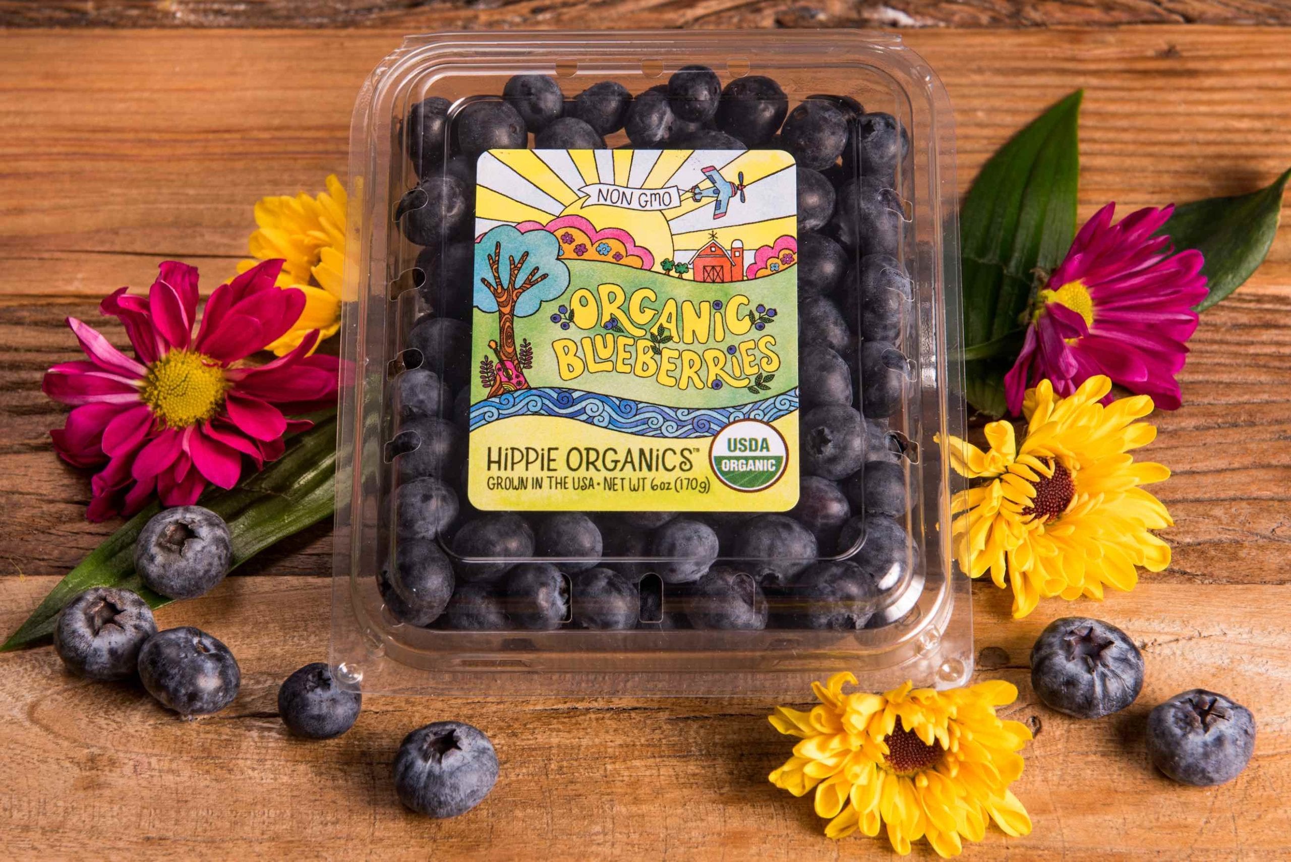 Aerial closeup view of package of organic blueberries surrounded by flowers