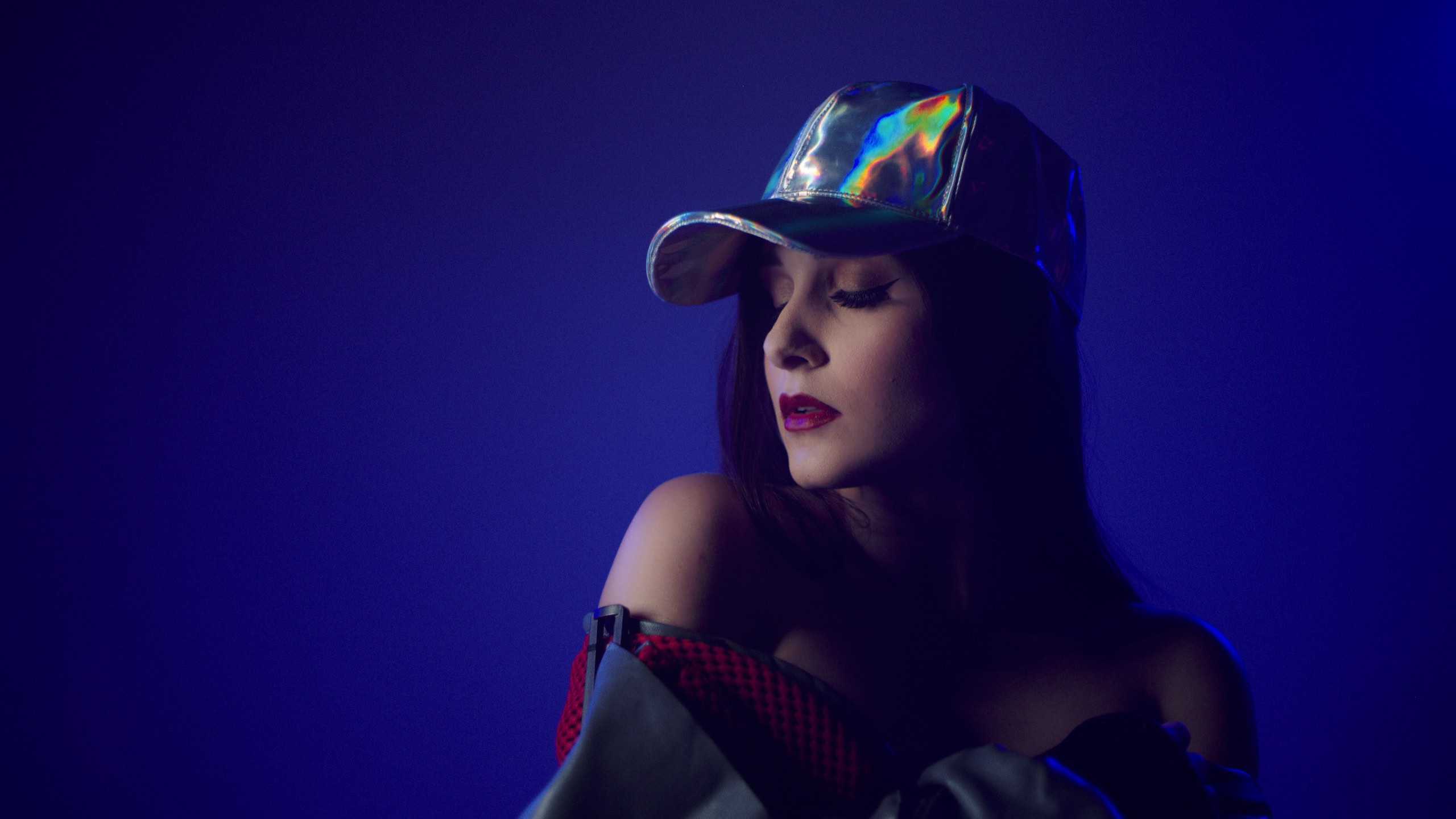 The Delorean Uncreative Music Woman with long hair wearing a multicolored cap, red and gray jacket and bright red lipstick headshot