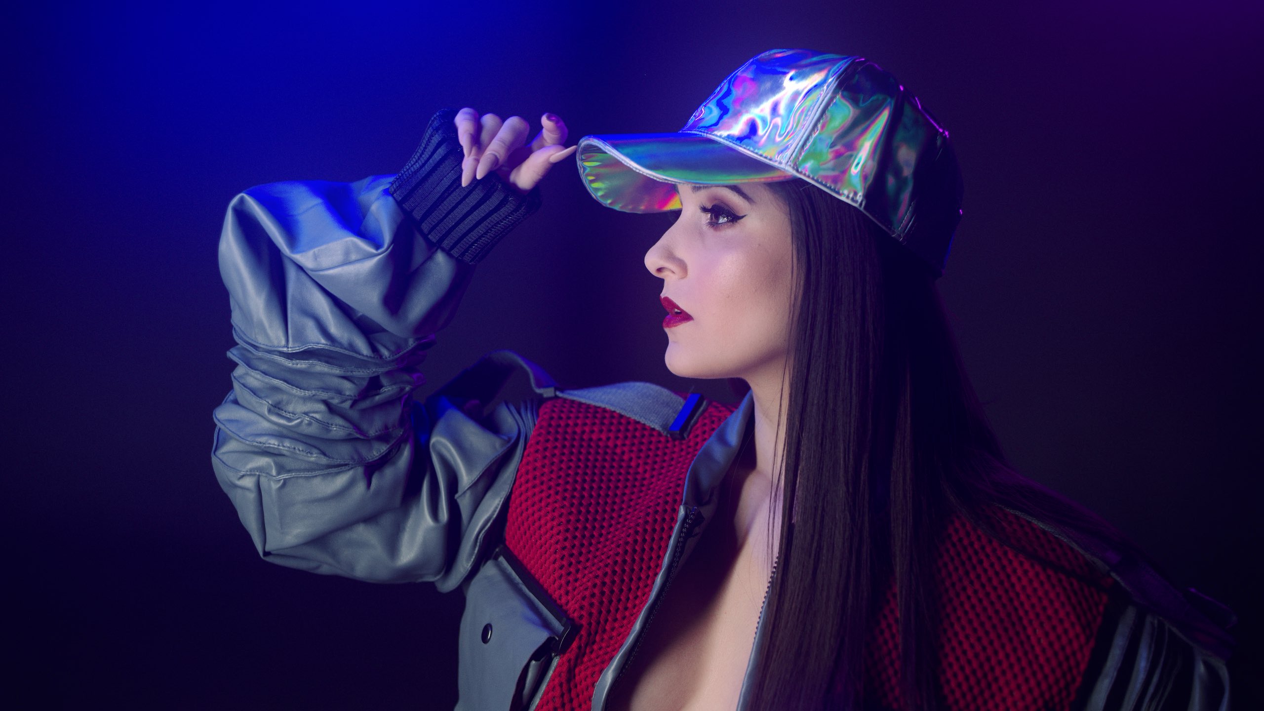 The Delorean Uncreative Music Woman holding her multicolored cap and wearing red and gray jacket