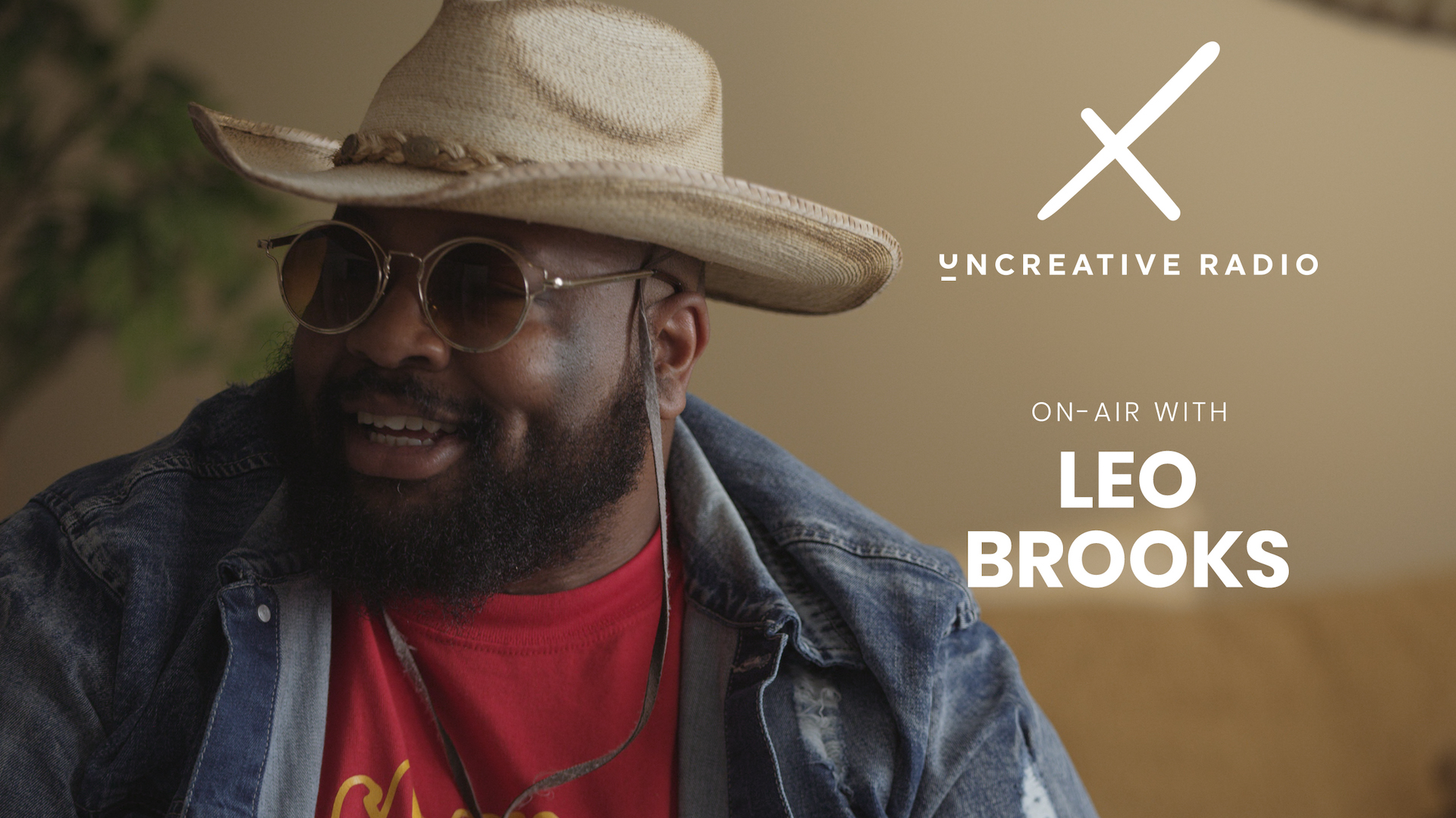 IU C&I Studios Page and Post Uncreative Radio with Leo Brooks title with bearded man wearing shades and beige cowboy hat along with jean jacket and red t shirt smiling looking off to the side