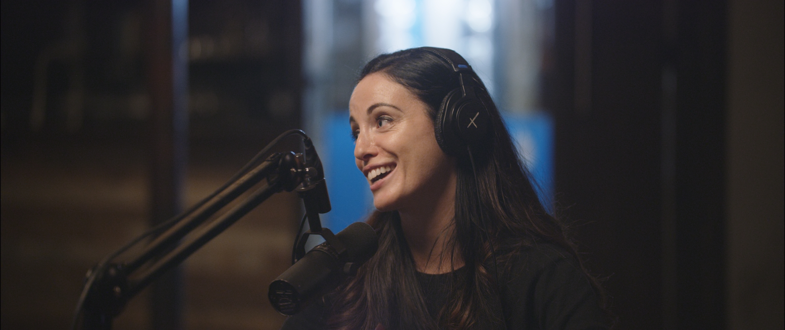 IU C&I Studios Post Uncreative Radio with Elisabetta Fantone with long hair wearing black headphones by the microphone smiling