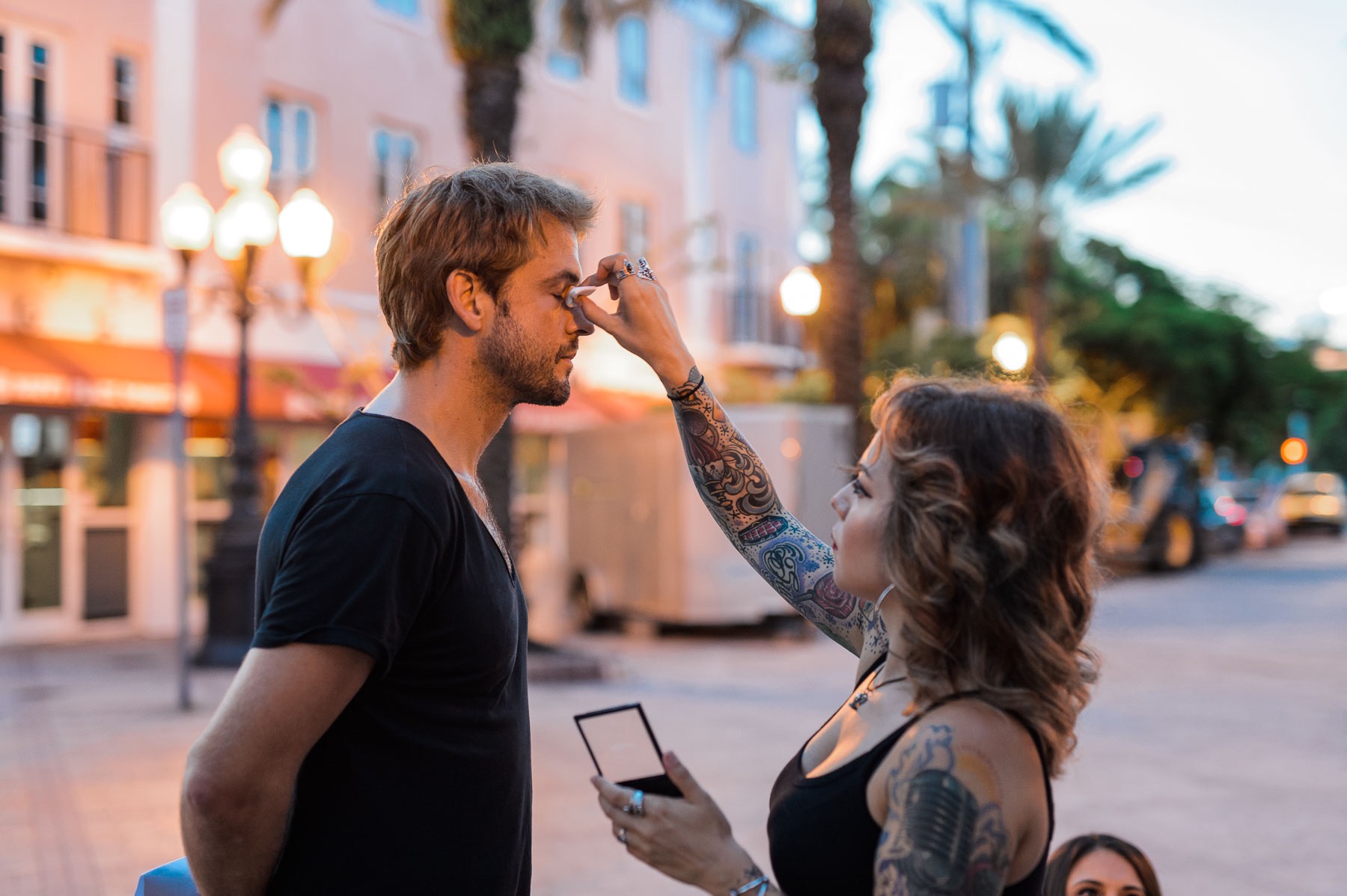 Love and War Feature film mastering and delivery services by C&I Studios Side profile of a tattooed female makeup artist putting finishing touches on a young male actor with short blond hair
