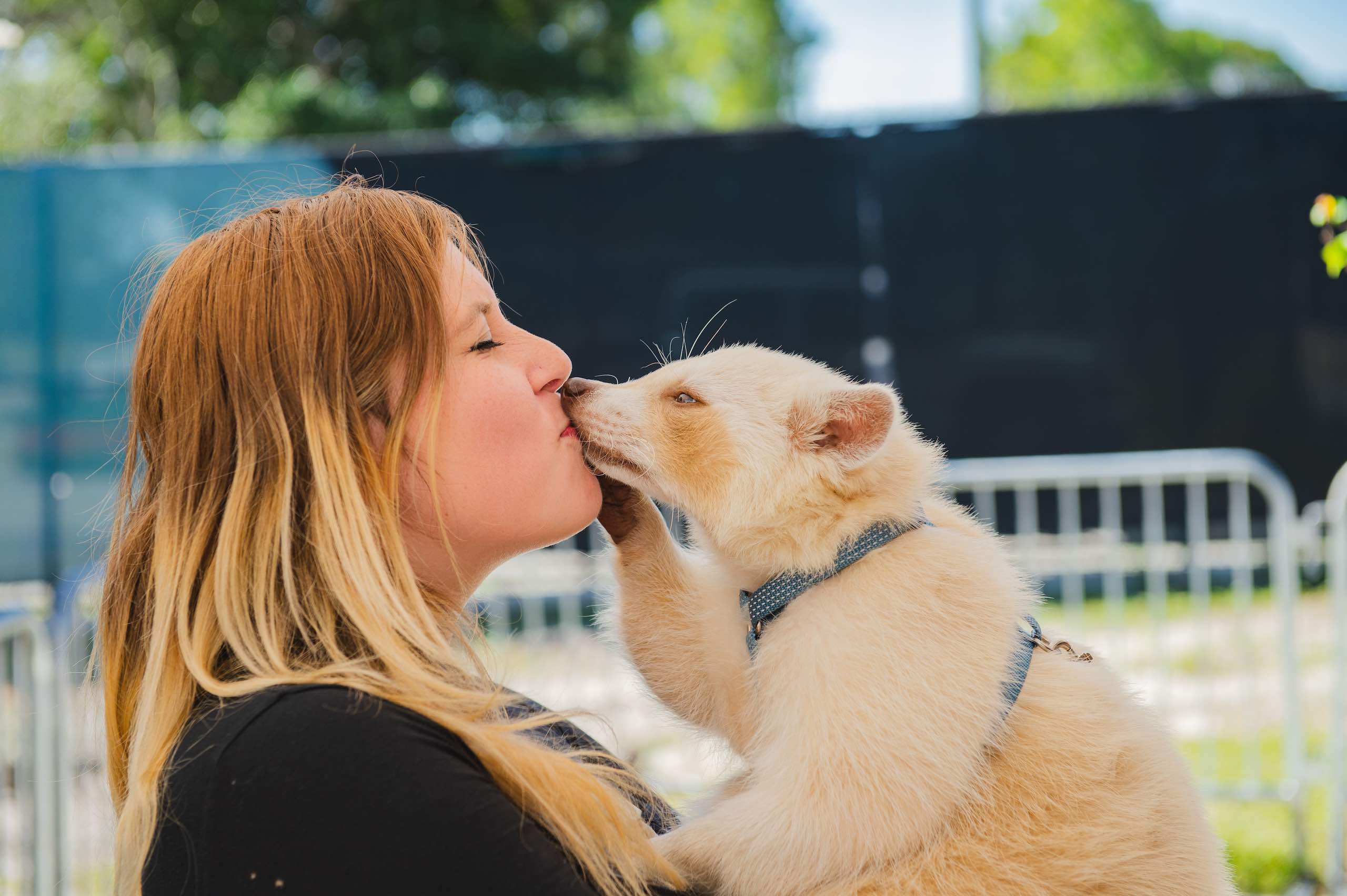 Everglades Holiday Park Side profile closeup of woman with long blond hair kissing a white raccoon wearing a blue leash collar