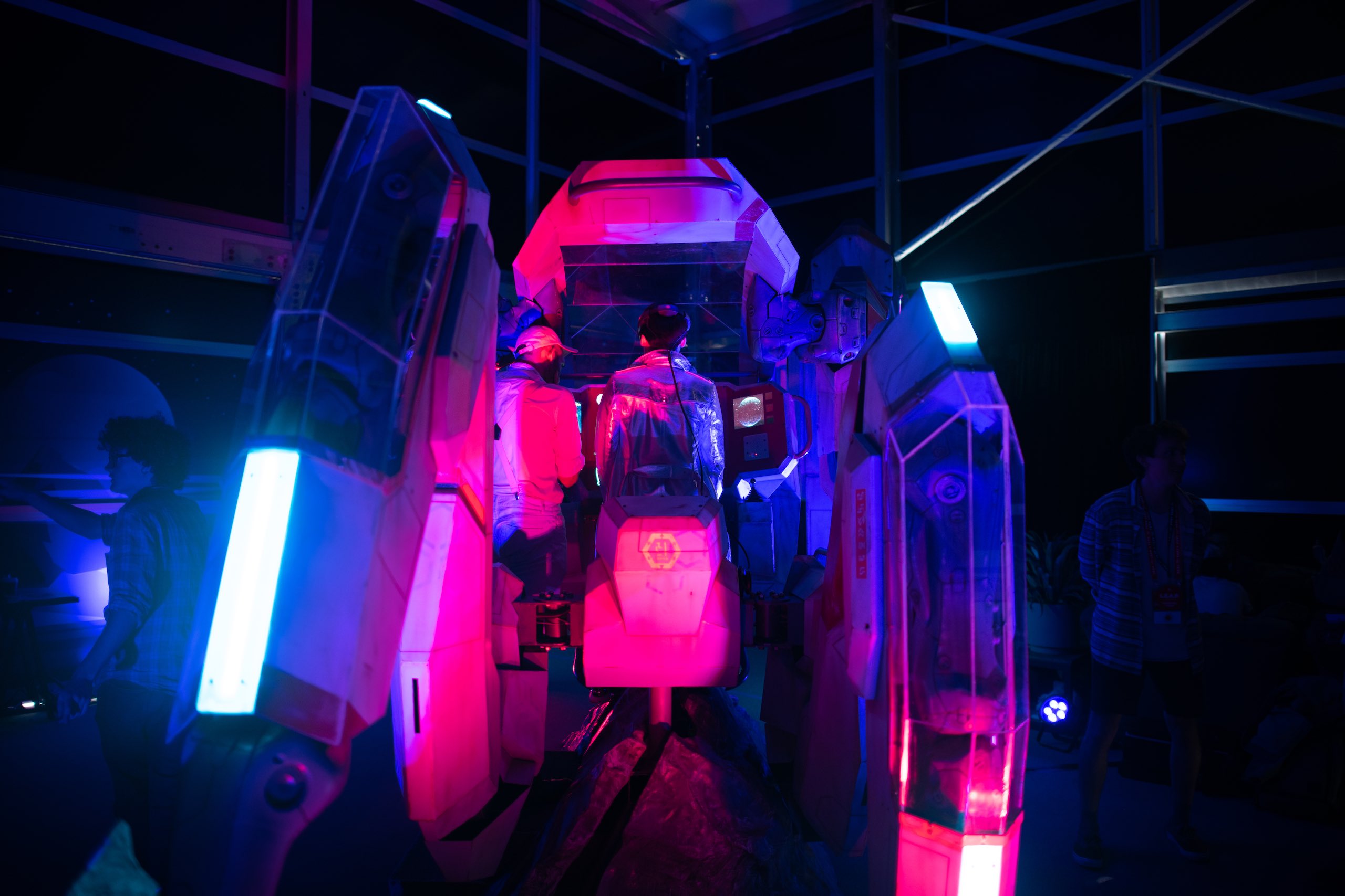 Two people in a futuristic simulator in reddish and bluish lights