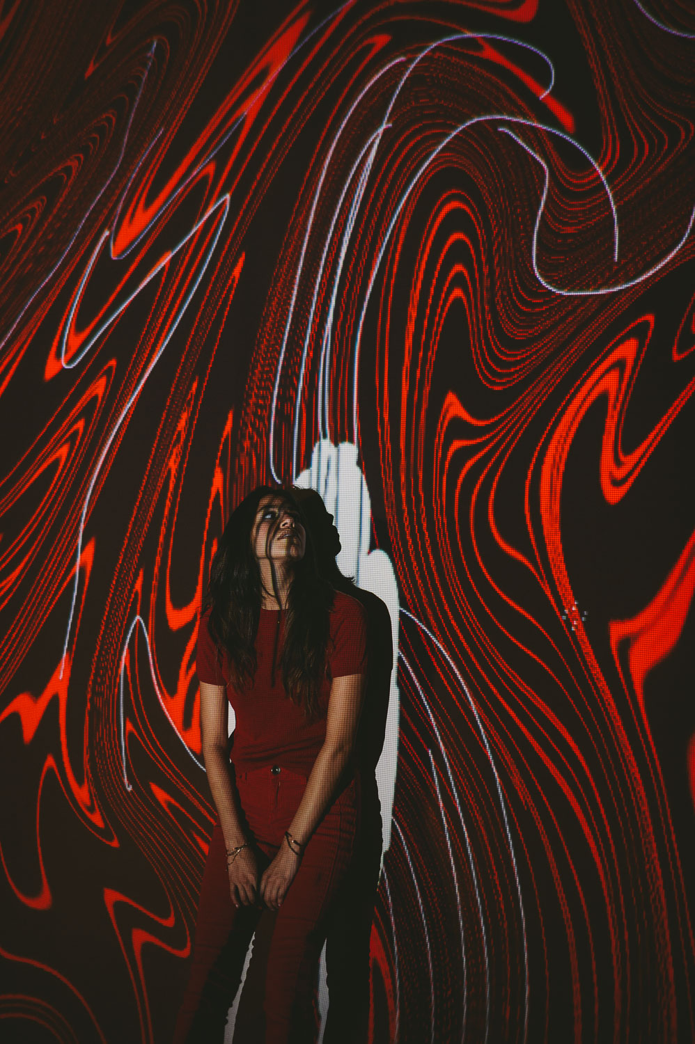Artwalk self projection live art exhibit by C&I Studios with woman with long black hair in front of red artwork looking up
