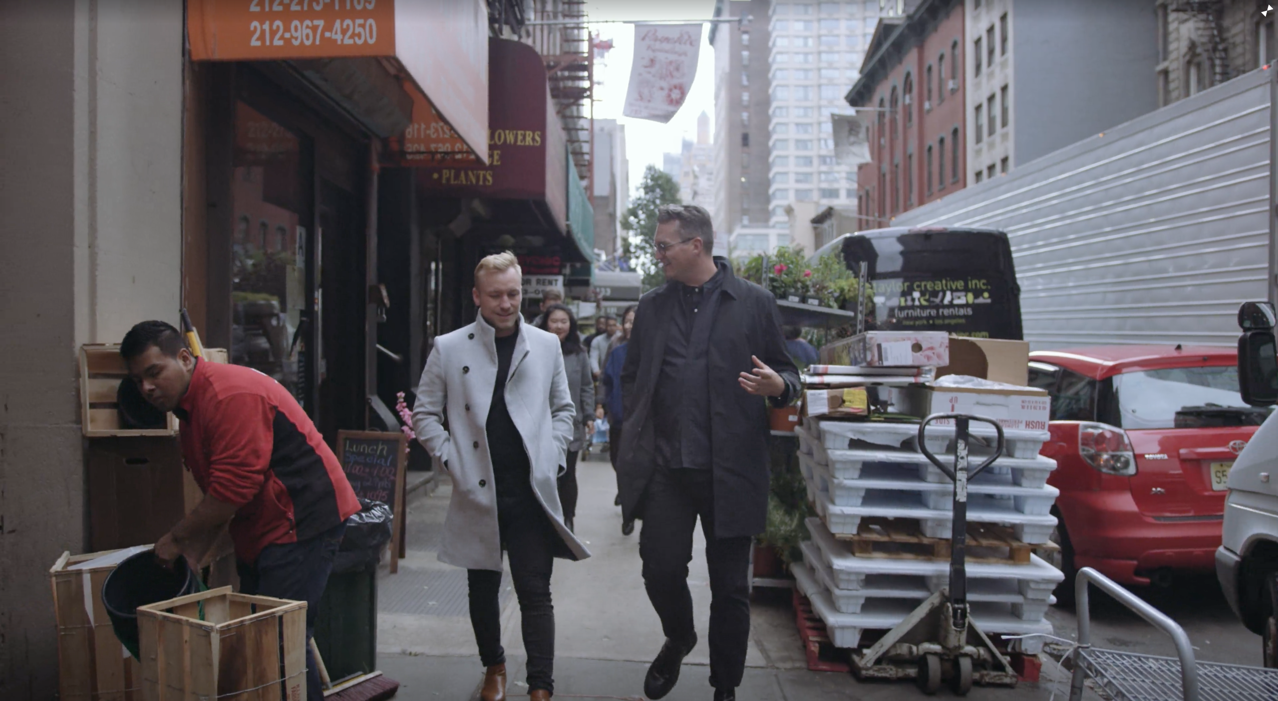 IU EDSA Design Studio NYC with two men walking down a street talking with cars parked nearby