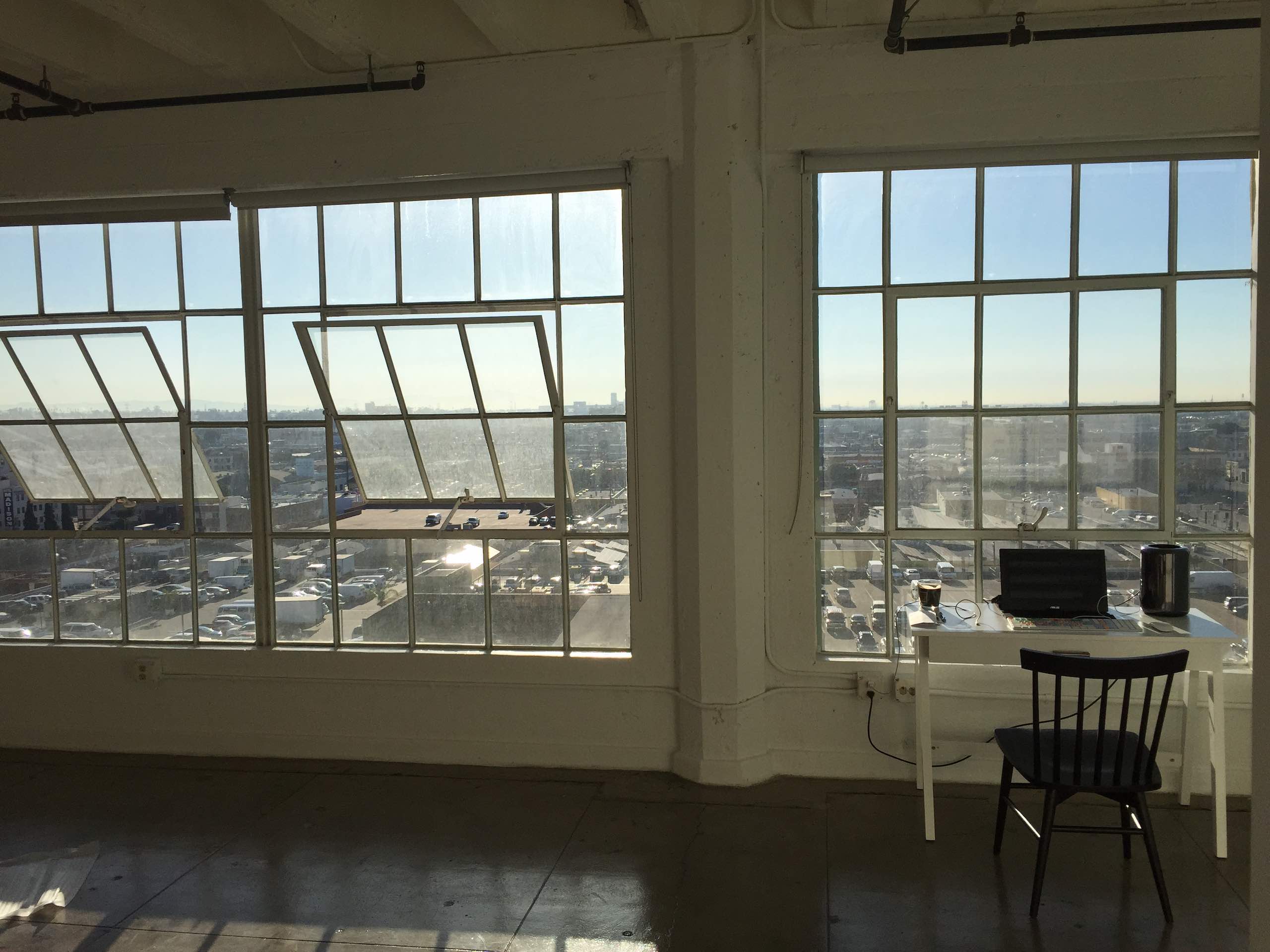 Studio Locations Downtown LA Loft with view looking out windows of a building over the city with table with computer and chair
