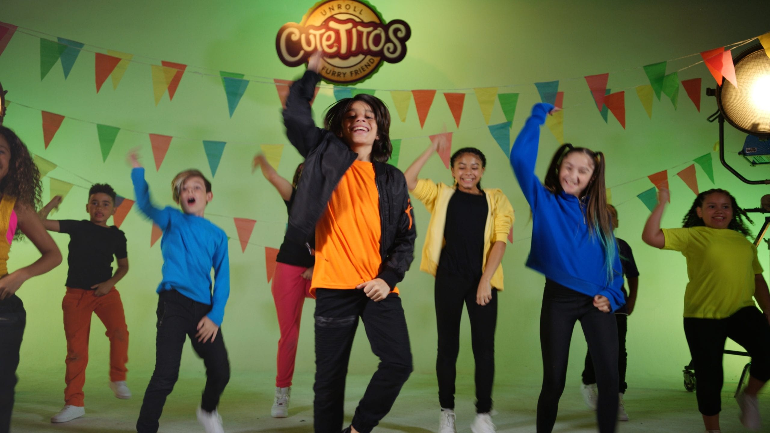 Group of smiling boys and girls dancing on set with a light green background