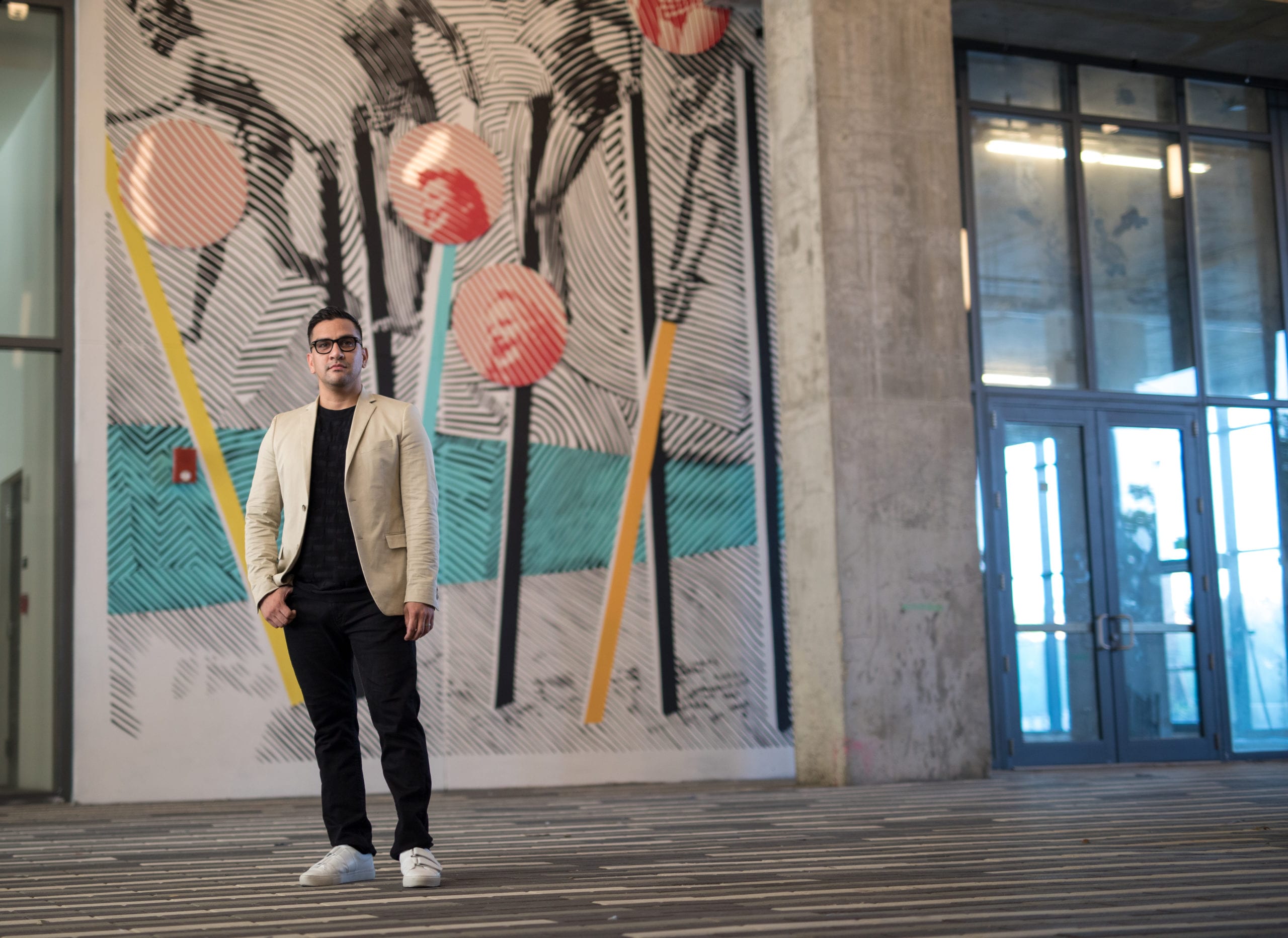 Fort Lauderdale Illustrated Men of Style Male model wearing glasses in a suit standing in front of artwork