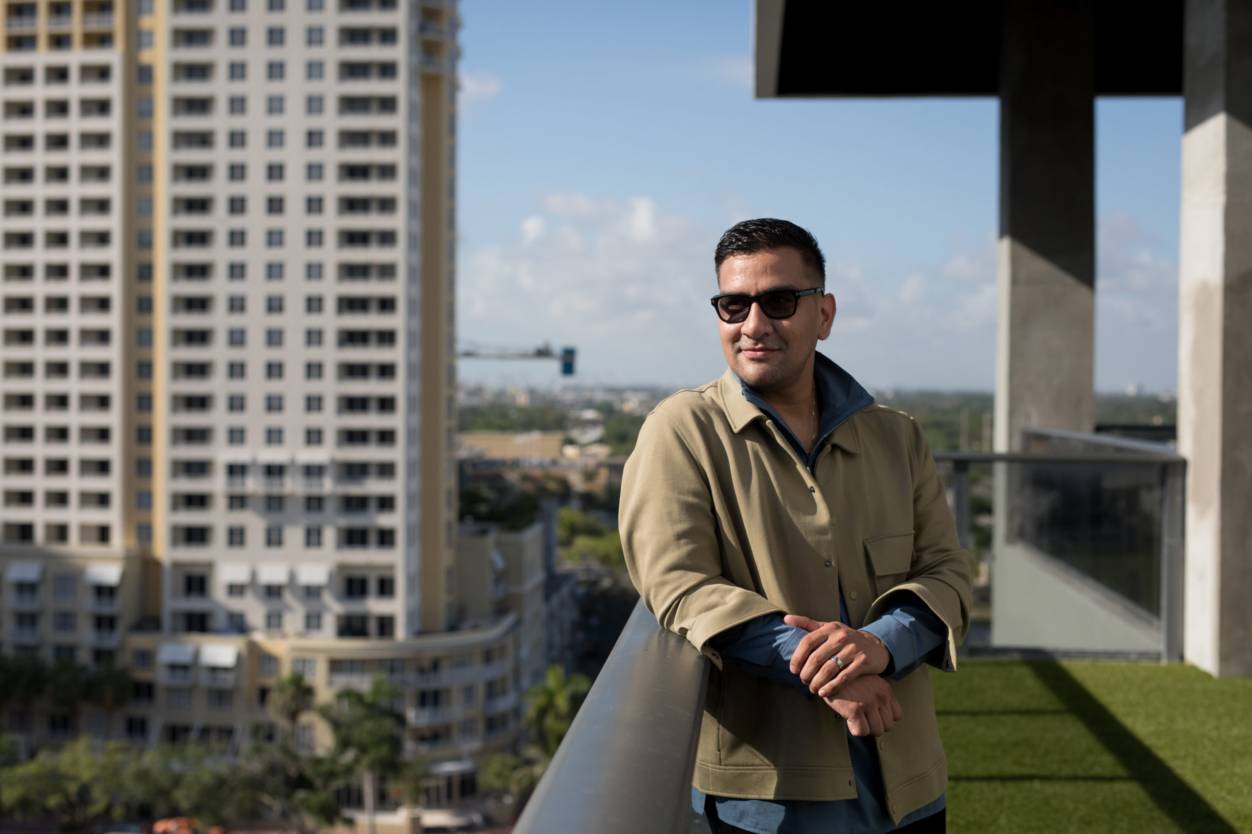Fort Lauderdale Illustrated Men of Style Closeup of male model wearing sunglasses standing on a balcony