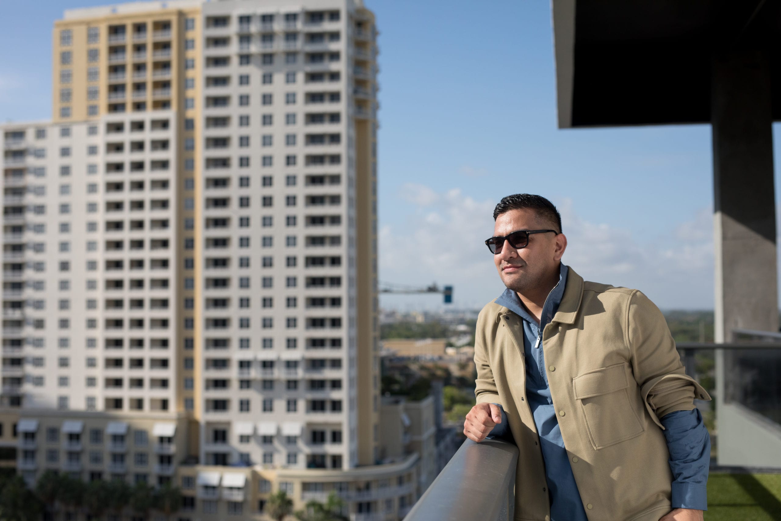 Fort Lauderdale Illustrated Men of Style Closeup of male model wearing sunglasses standing on a balcony