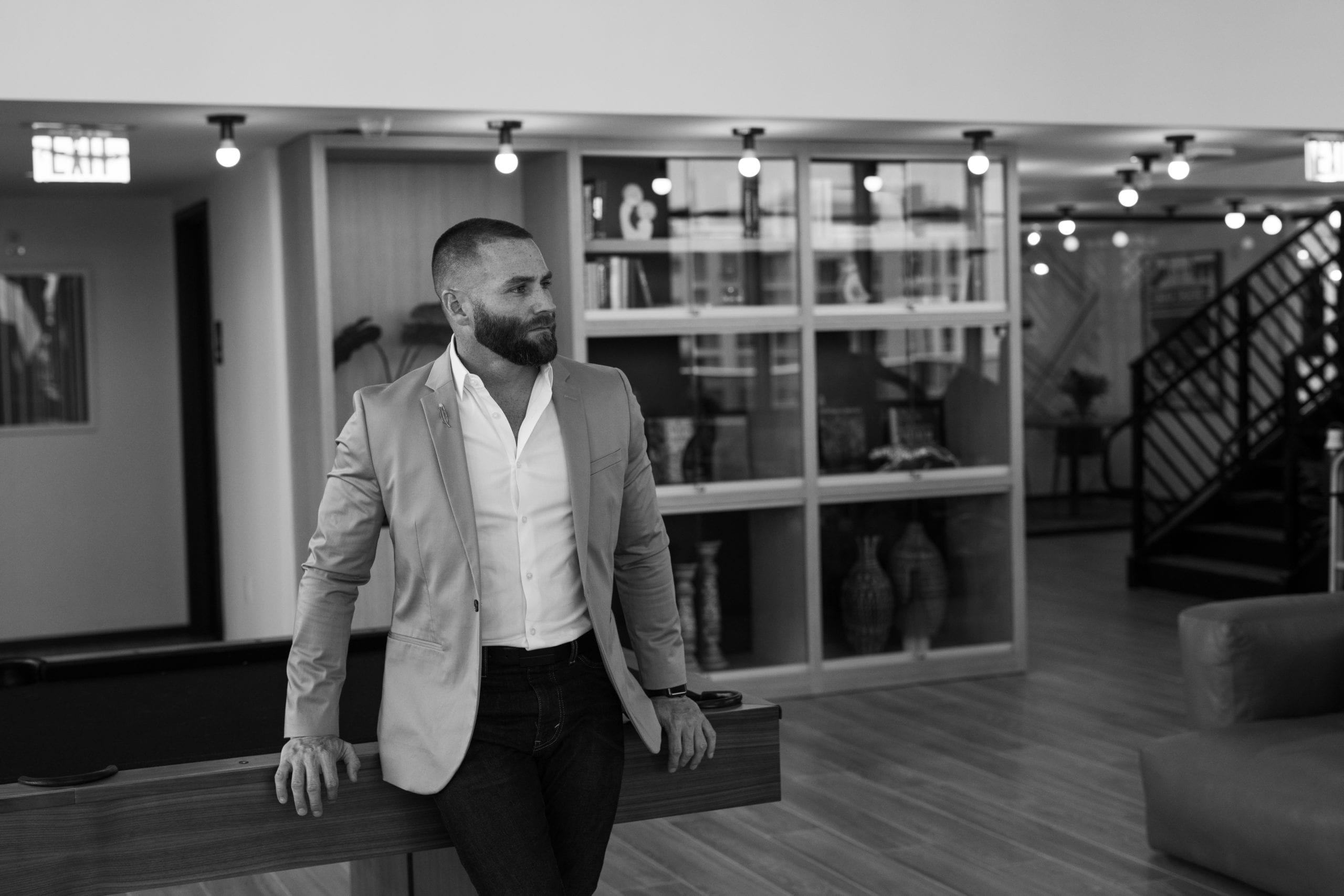 Fort Lauderdale Illustrated Men of Style Black and white of male model with beard in a suit leaning back on a pool table looking off to the side