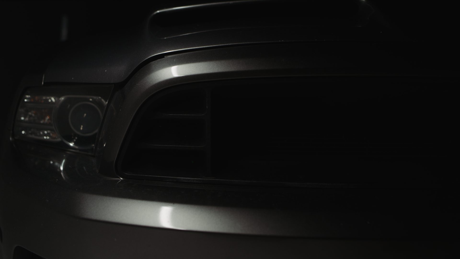 Closeup view of front of a gray car in semidarkness